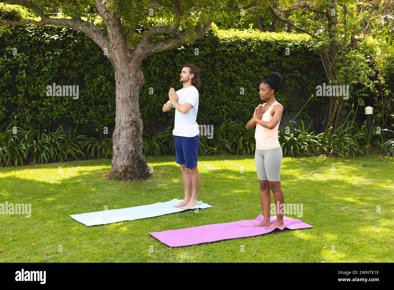 A diverse couple, a young Caucasian man and an African American woman, practice yoga outdoors Stock Photo