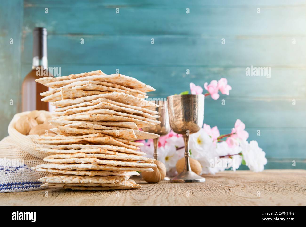 Passover celebration concept. Matzah, red kosher and walnut on wooden vintage table in front of spring blossom tree garden and flowers landscape with Stock Photo