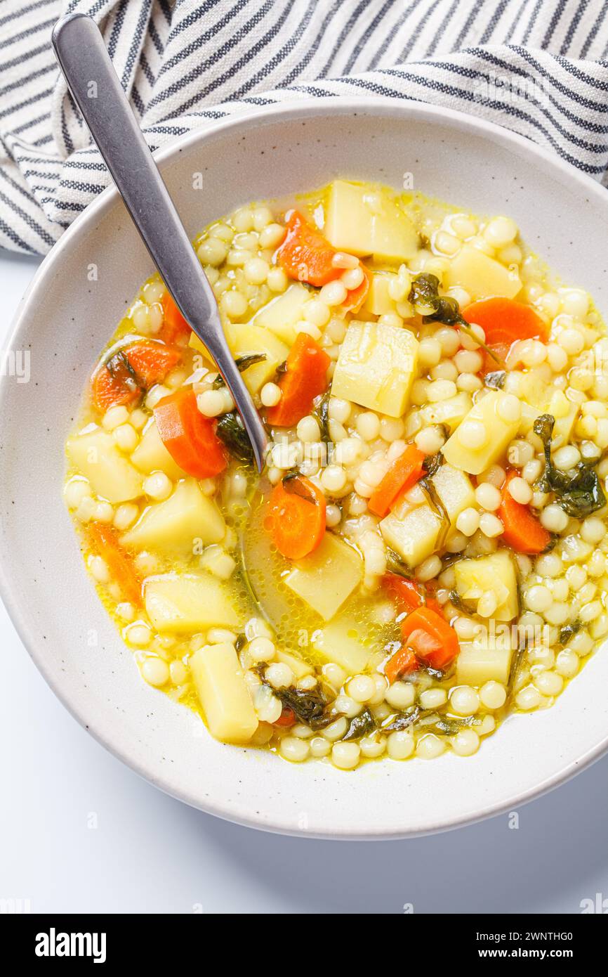 Traditional Israeli soup with ptitim, vegetables and spinach. Stock Photo
