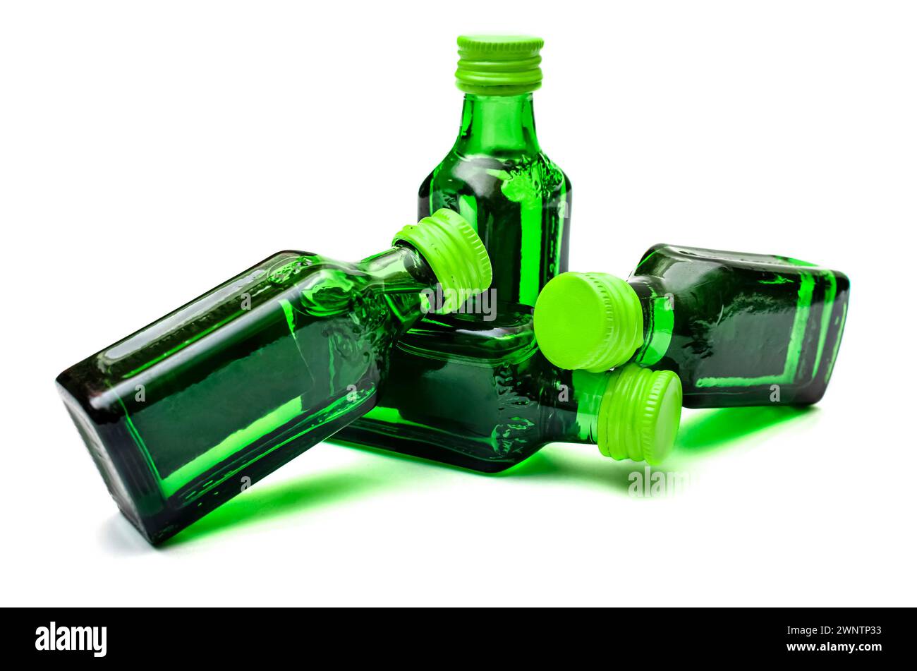 Close-up of Four small bottles of green colored alcohol on an isolated background Stock Photo