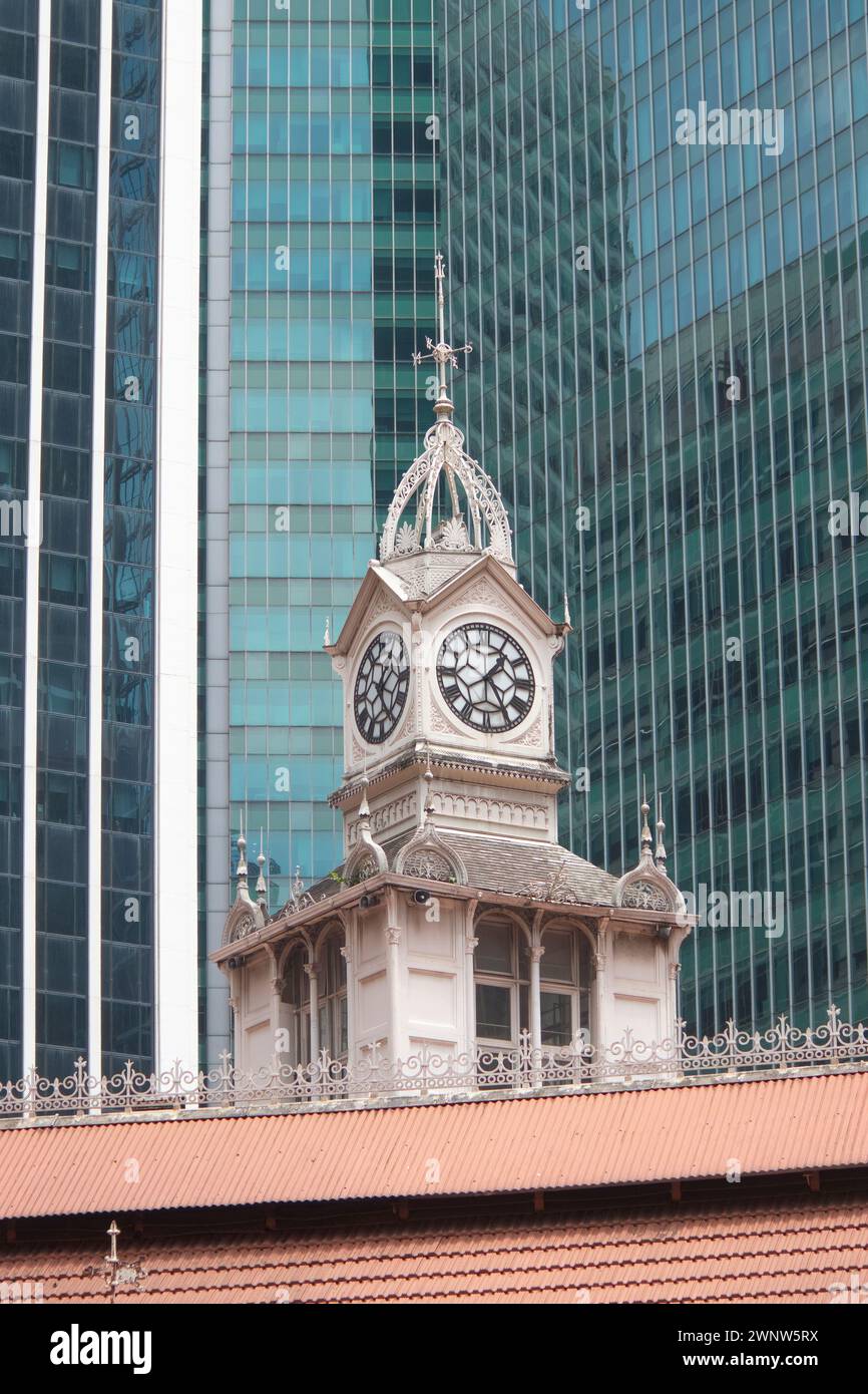Colonial style clock tower at Lau Pa Sat the food hawker centre in Singapore contrast to the modern glass tower blocks behind it architecture Stock Photo