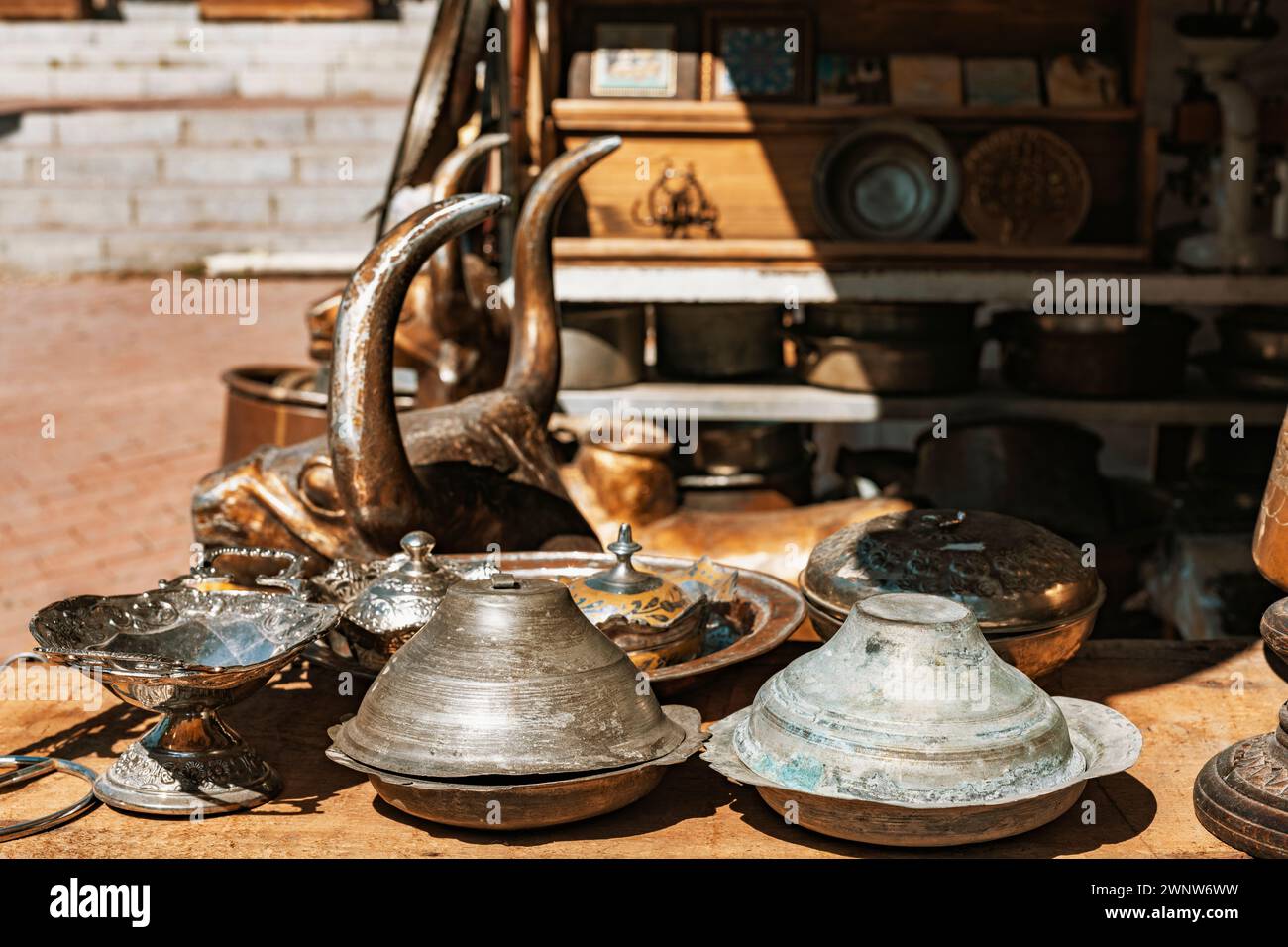 Vintage bronze animal statue, mortars, silver and copper plates, frames and other ornaments on counter top in a shop at bazaar. Stock Photo