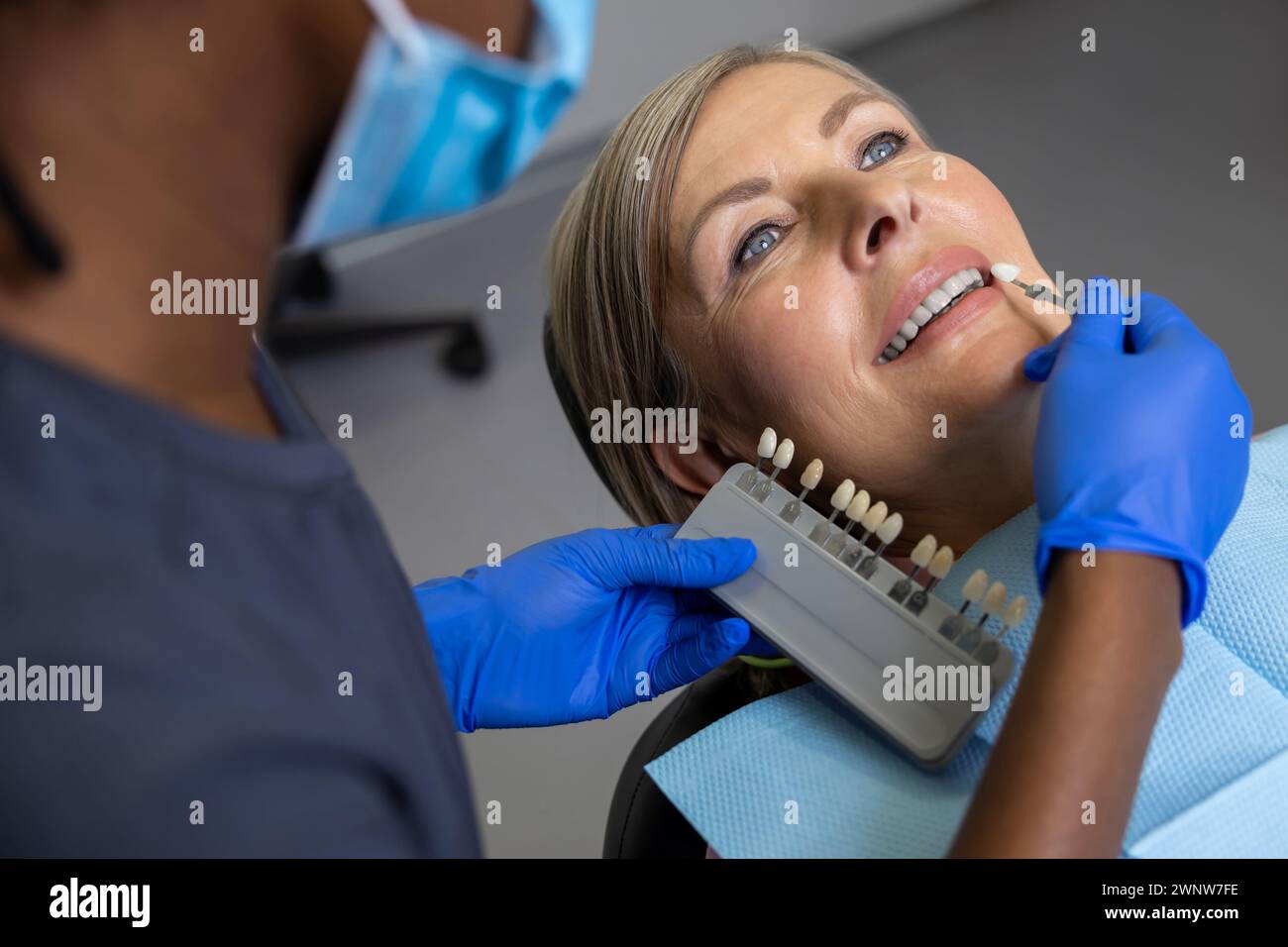 Woman dentist holding dental teeth shade guide chart choosing right