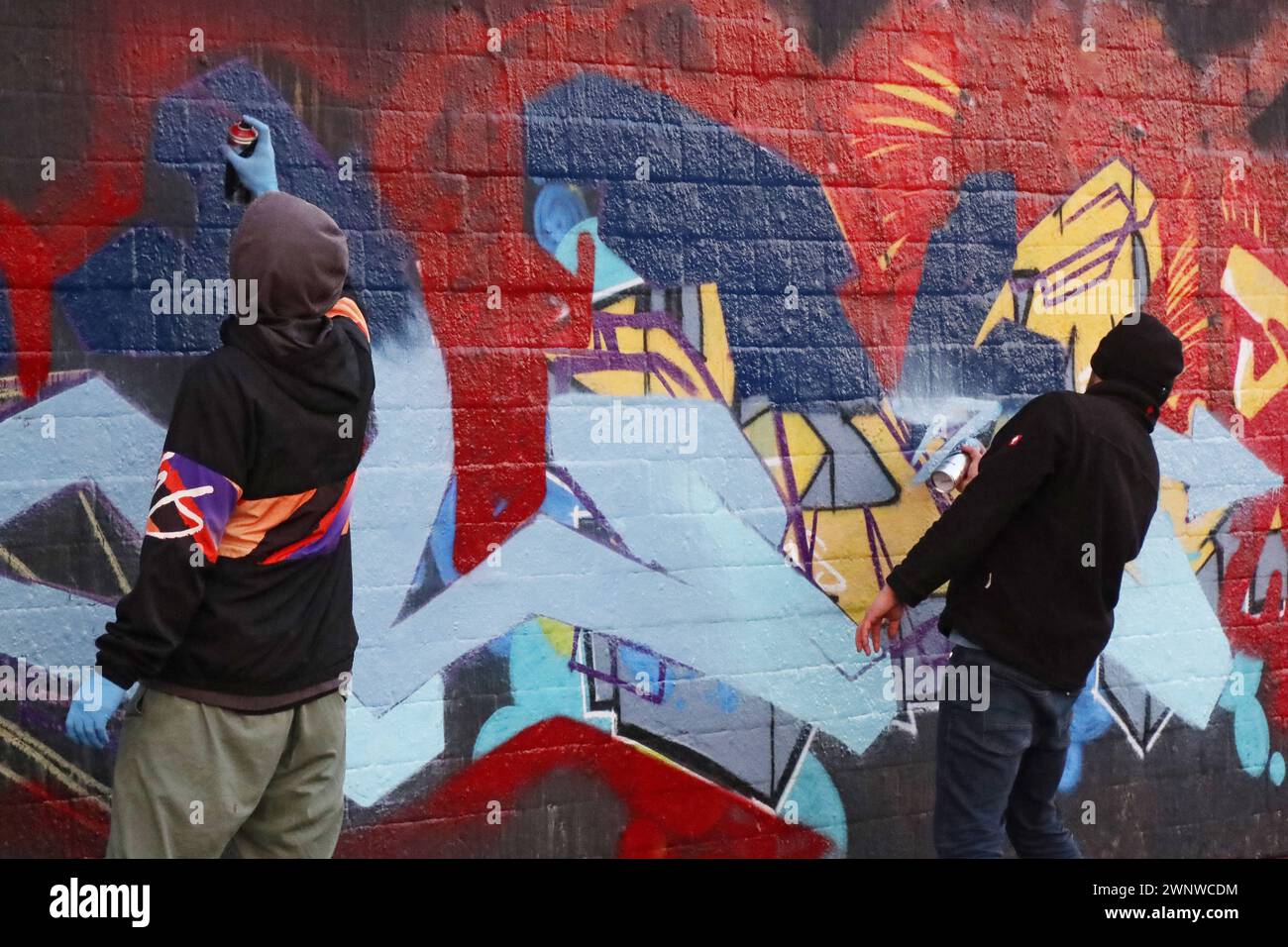 27.12.2022, Berlin, GER - Jugendliche spruehen Graffiti an eine Wand. Aktivitaet, Alltag, aussen, Aussenaufnahme, bemalen, Bemalung, Berlin, beschmieren, bespruehen, deutsch, Deutschland, Europa, europaeisch, Farbe, farbig, Freizeit, Gesellschaft, Graffiti, Grafitti, Haeuserwand, Hobby, Jahreszeit, Jugend, Jugendliche, Kultur, Kunst, malen, Malerei, Mauer, Menschen, Personen, Problem, QF, Querformat, Sachbeschaedigung, schmieren, Schmiererei, Schmierereien, Sprayer, Spraykunst, spruehen, Stadt, Stadtbild, Stadtlandschaft, Strasse, Strassenkunst, Street-Art, Szene, Vandalismus, Wand, Westeuropa Stock Photo