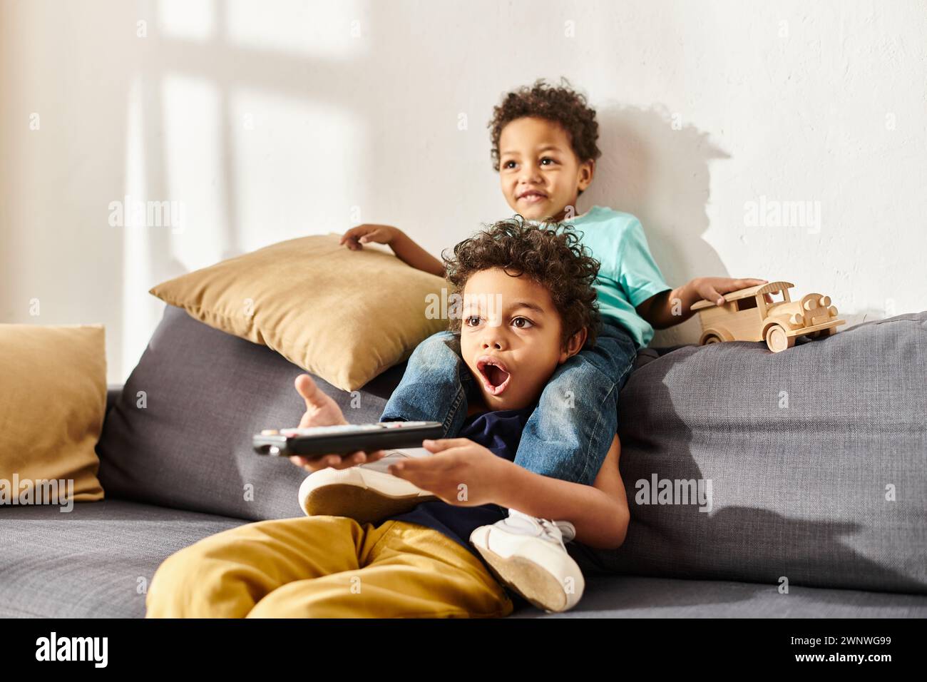 shocked african american boy holding remote control and watching movies ...