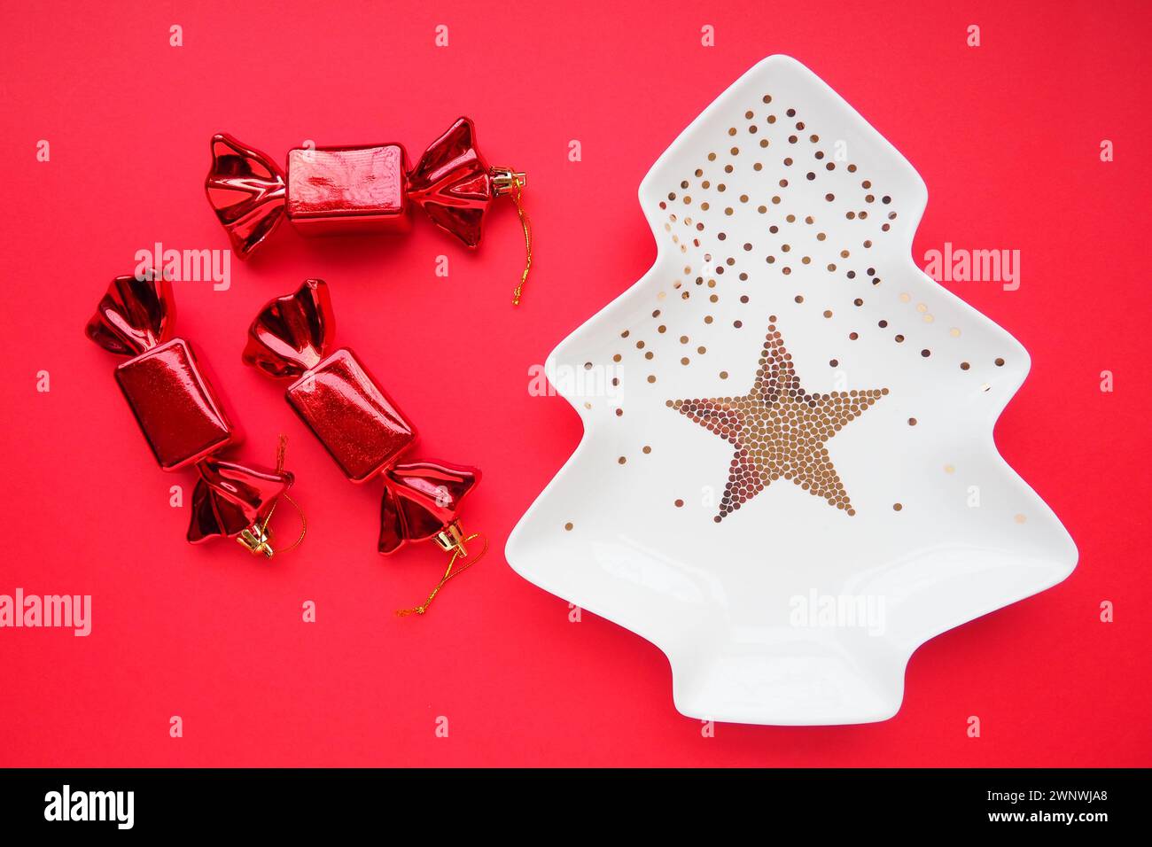 Christmas tree with gold ornaments and a star in the middle. Red background. Candy in a red shiny wrapper. Background for advertisements and Stock Photo