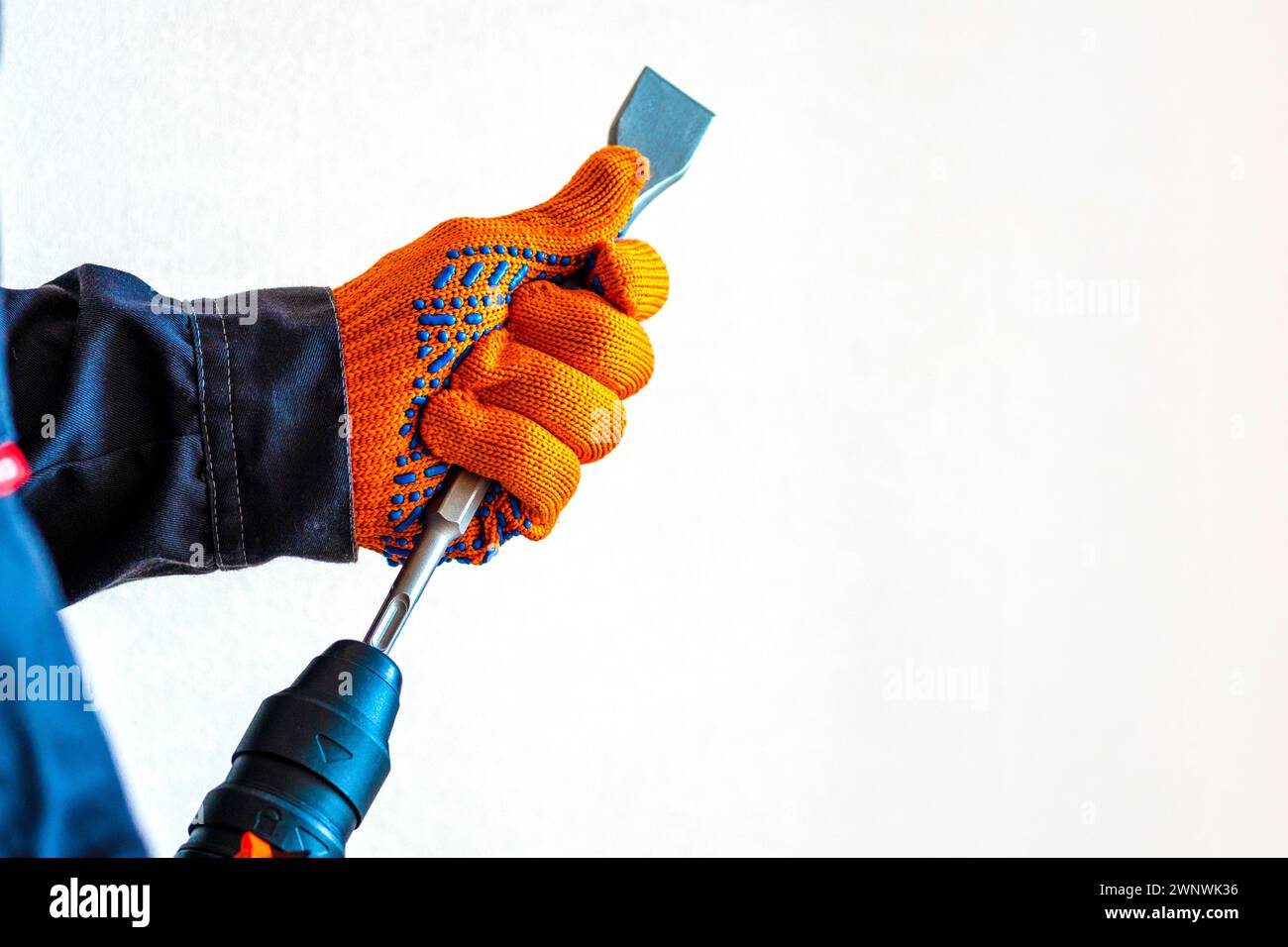 close-up. hands in protective gloves, hammer drill, installation of a chisel in a perforator. The concept of replacing the rotary drill. Stock Photo