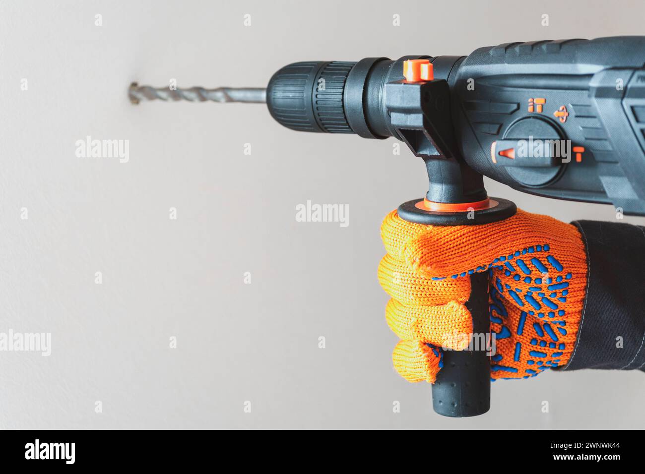 workman hand with a rotary hammer. Hands in protective gloves with ...