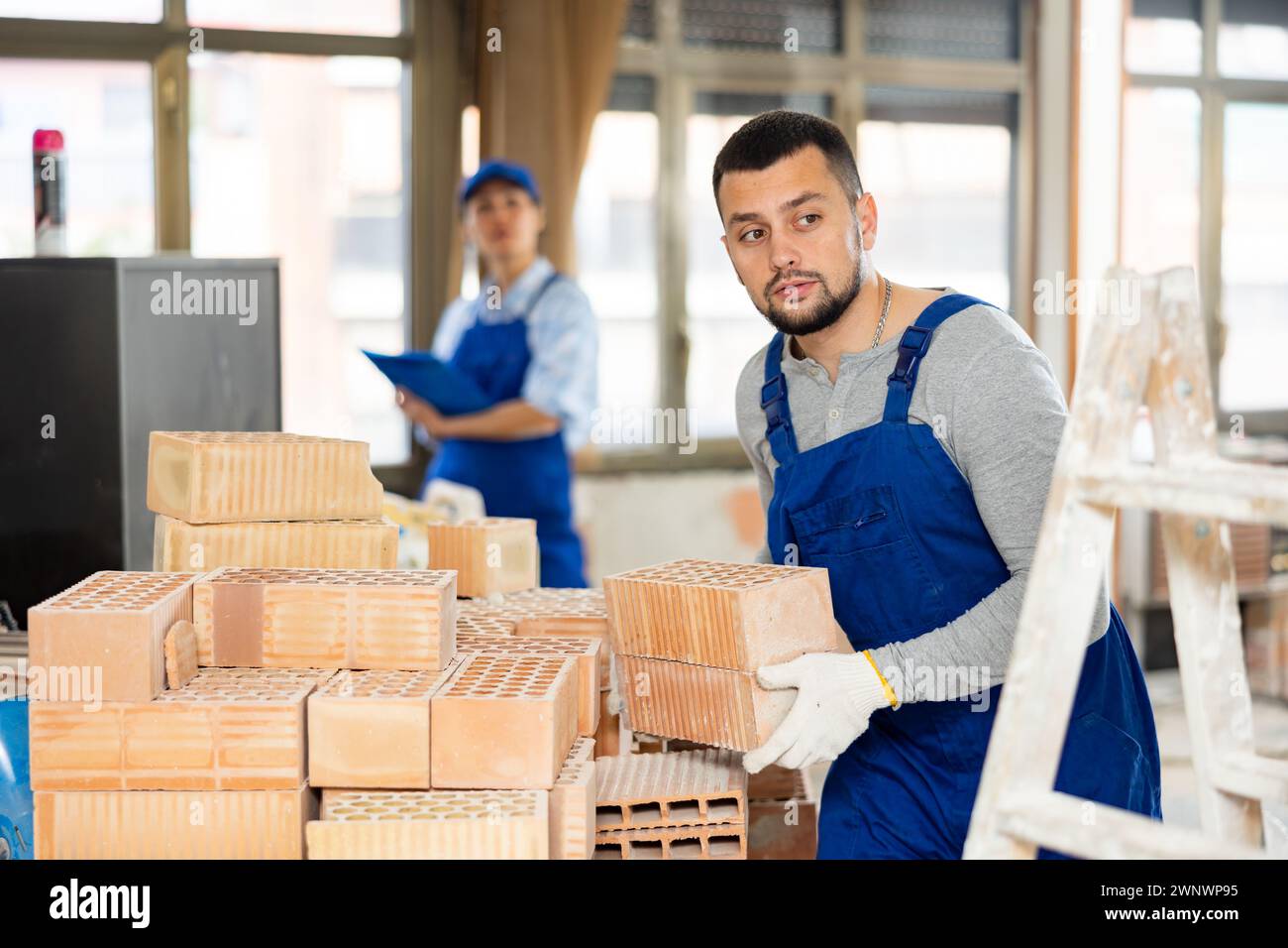 Builder carrying bricks while working in apartment Stock Photo