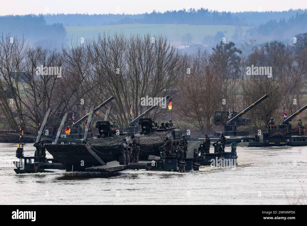 Korzeniewo, Poland on March 4, 2024. German flagged NATO soldiers exercise ability to cross Boxer armored vehicles through Vistula river on ferries during NATO's  Dragon-24 exercise, a part of large scale Steadfast Defender-24 exercise. The Steadfast Defender-2 exercises, which will take place mainly in Central Europe, will involve some 90,000 troops from all NATO countries as well as Sweden. Their aim is to deter and present defensive abilities in the face of aggression. Stock Photo