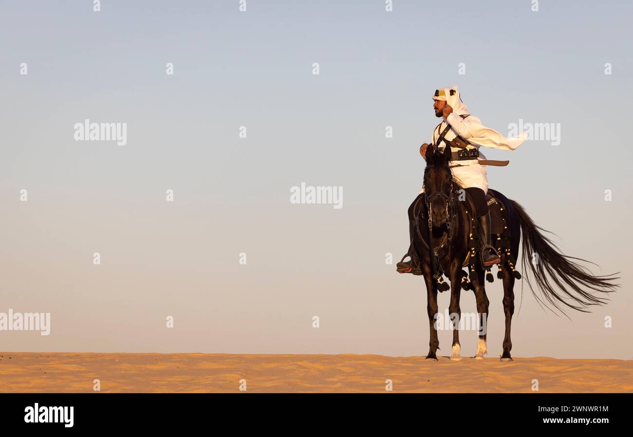Saudi man in a desert with his black horse Stock Photo