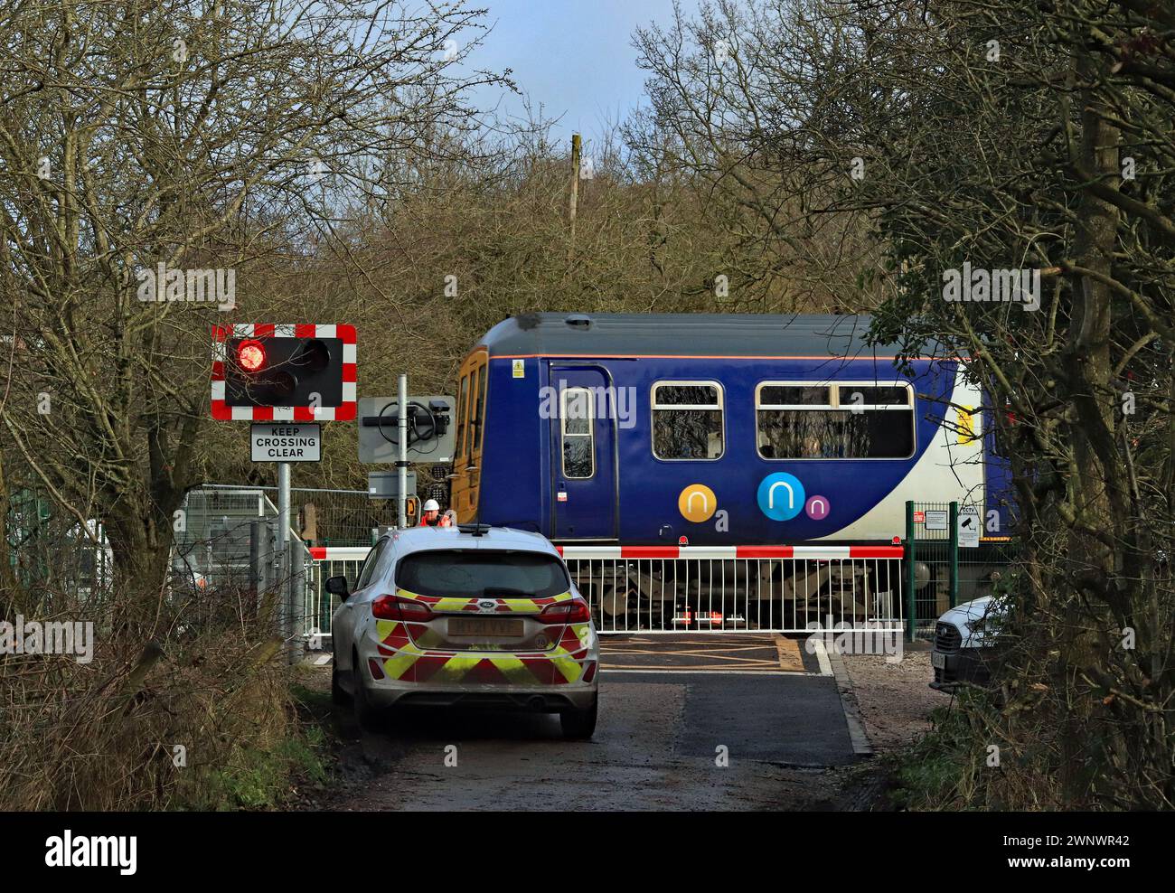 A Northern train going to Southport crosses the level crossing at Chapel Lane, Parbold, Lancashire where new automatic barriers have been installed. Stock Photo