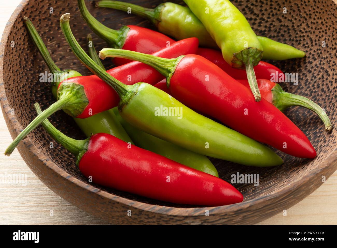 Bowl with whole fresh raw green and red rawit hot peppers close up Stock Photo