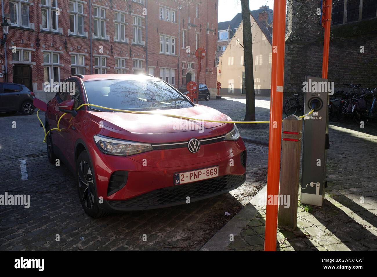 Bruges, Belgium - Feb 27 2024 Red Volkwagen electric car is charging. It's a sunny day in winter Stock Photo