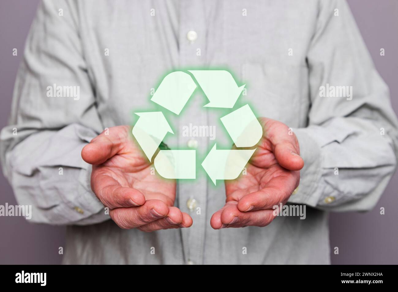 Close-up of an unrecognizable person's hands holding a floating recycling symbol. Stock Photo