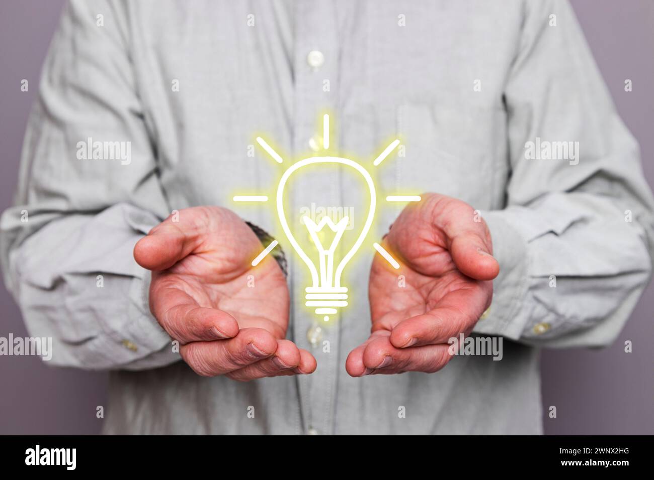 Close-up of an unrecognizable person's hands holding a floating light bulb shape. Stock Photo