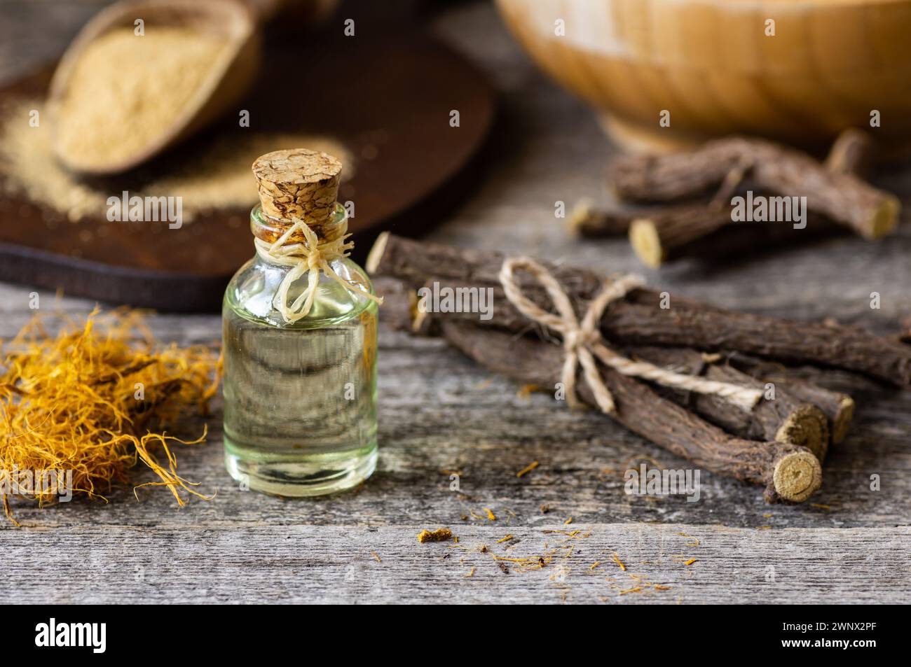 Glass bottle of licorice root essential oil with liquorice fiber on rustic background ( glycyrrhiza glabra ) Stock Photo