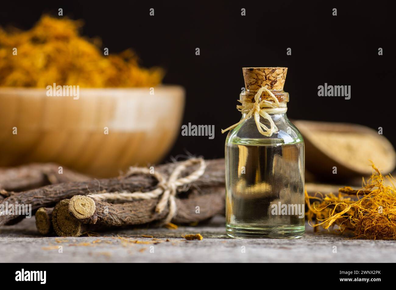 Glass bottle of licorice root essential oil with liquorice fiber on