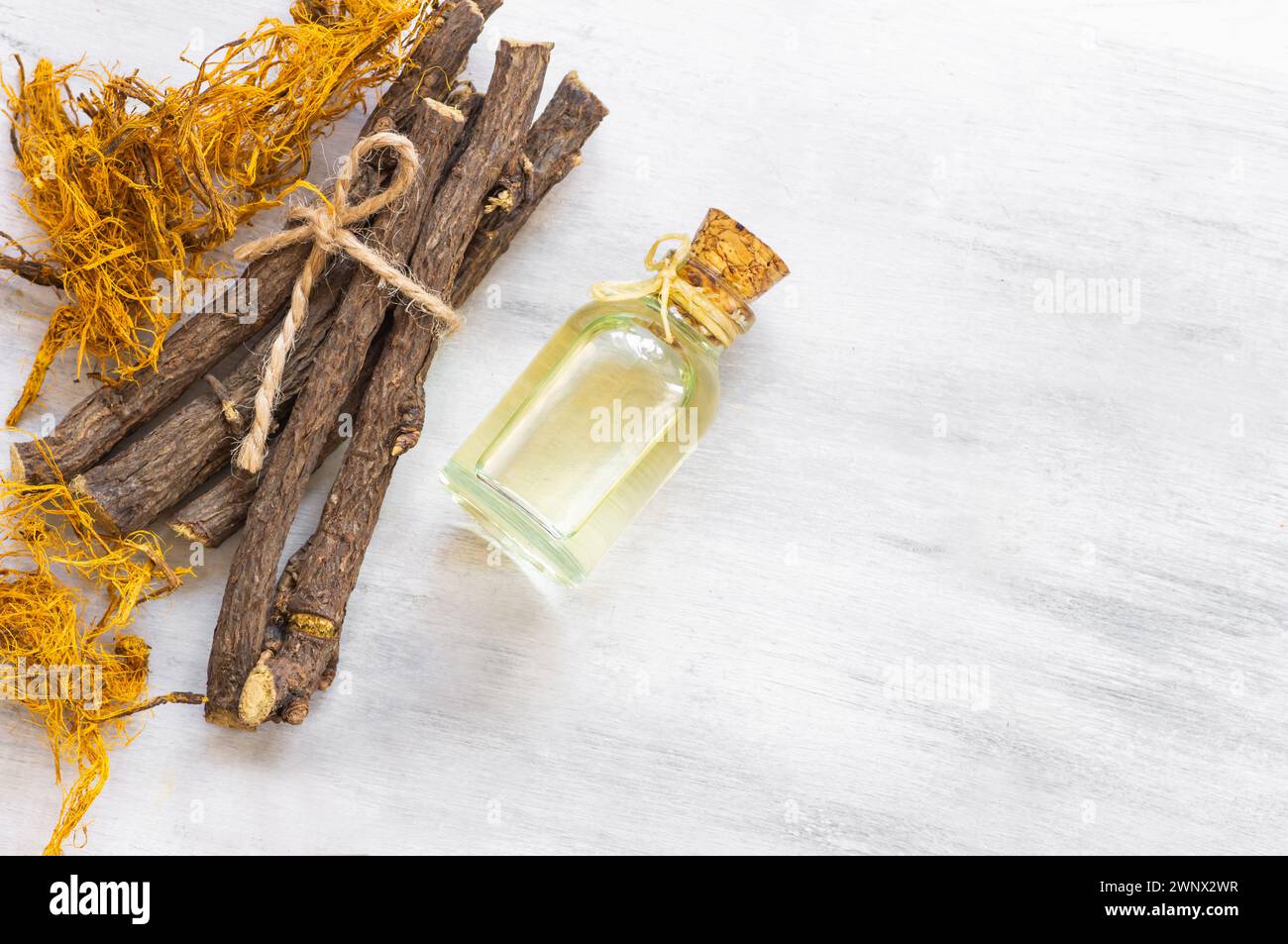 Glass bottle of licorice root essential oil with liquorice fiber on