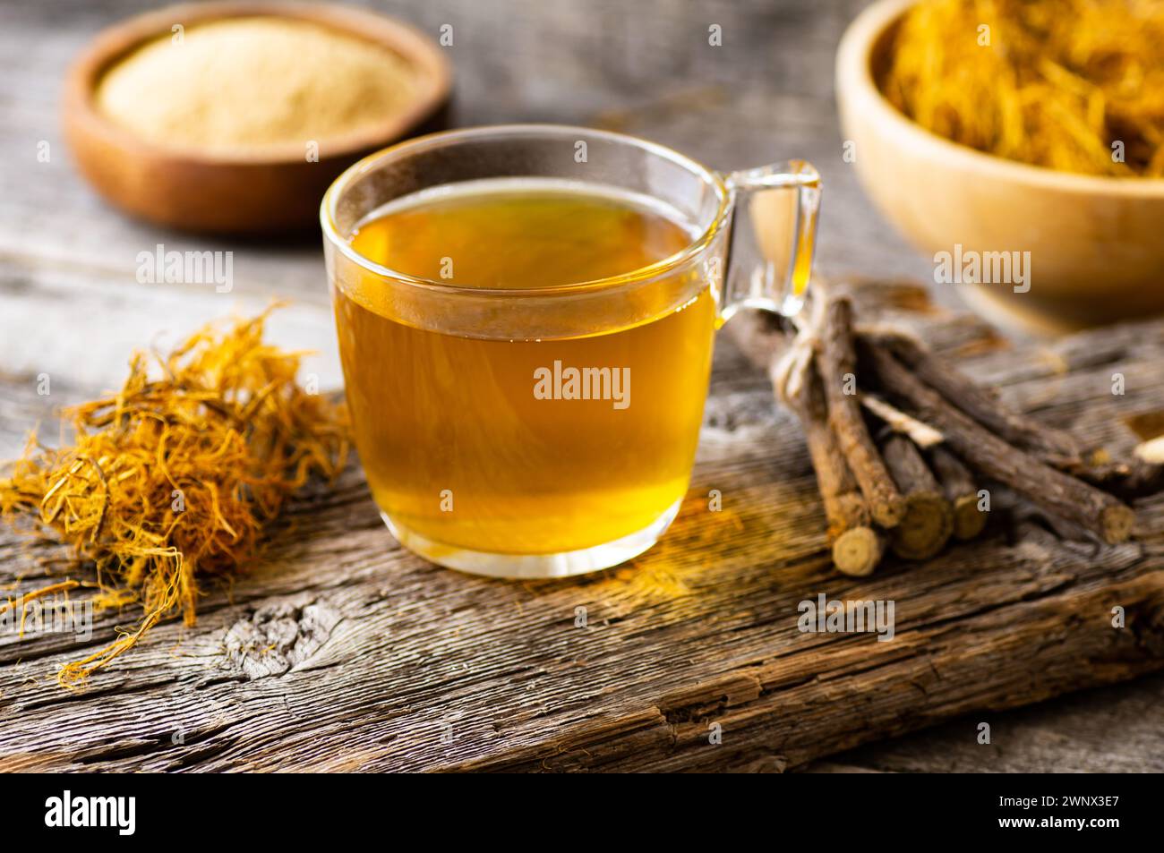 Glass cup of licorice tea with licorice root and fiber on rustic background, alternative medicine ( glycyrrhiza glabra ) Stock Photo