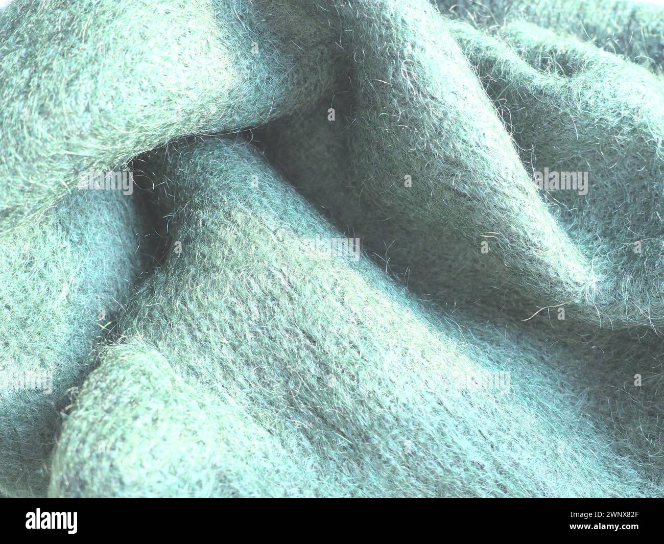 Knitted wool background. Warm winter clothes tied from green yarn brand ...