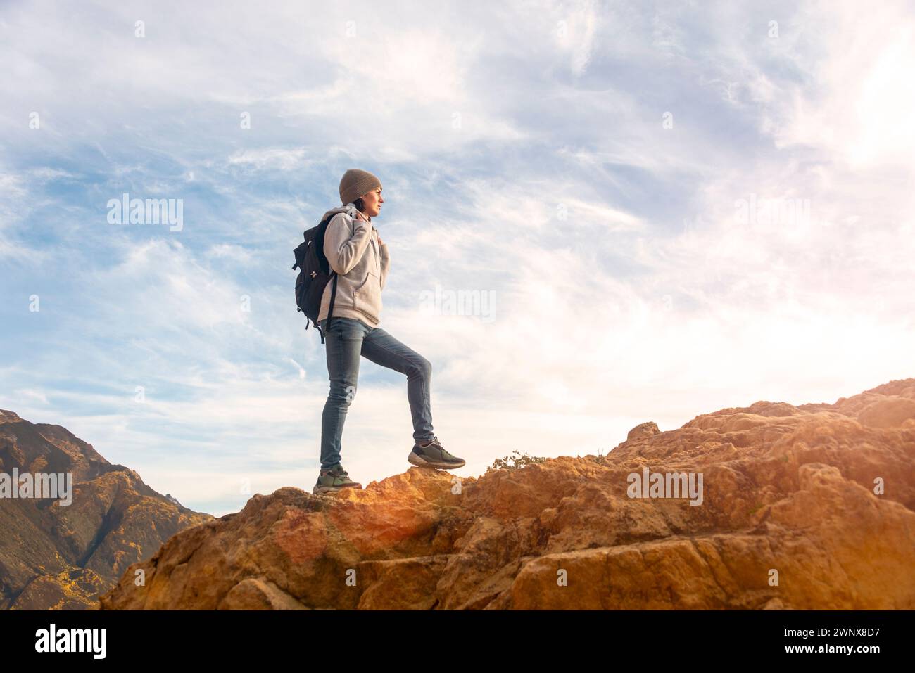 woman hiker with backpack walking up rocks, getting away from it all concept. Stock Photo