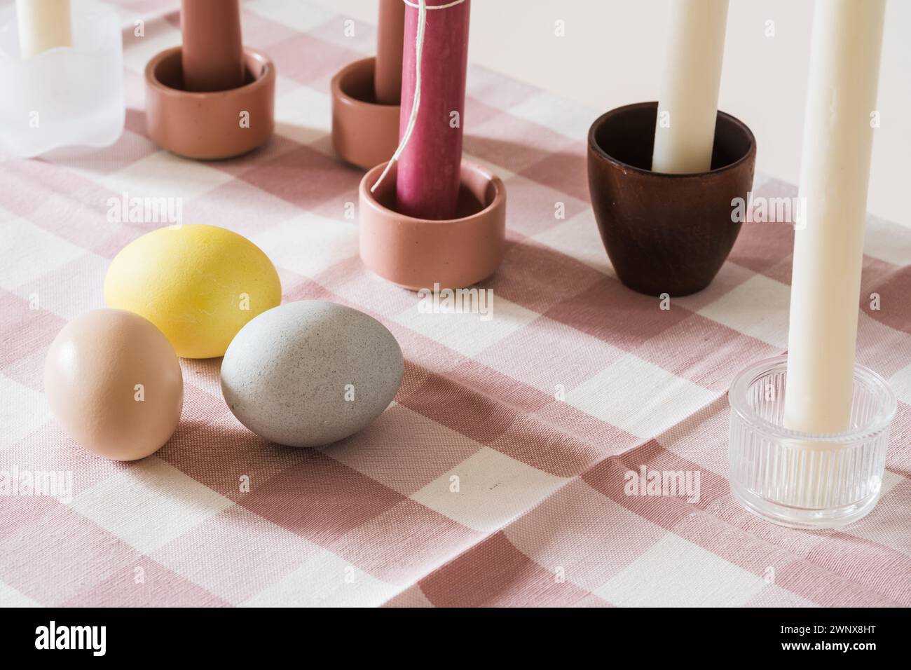 Easter place setting with candles and multi colored eggs, linen tablecloth Stock Photo
