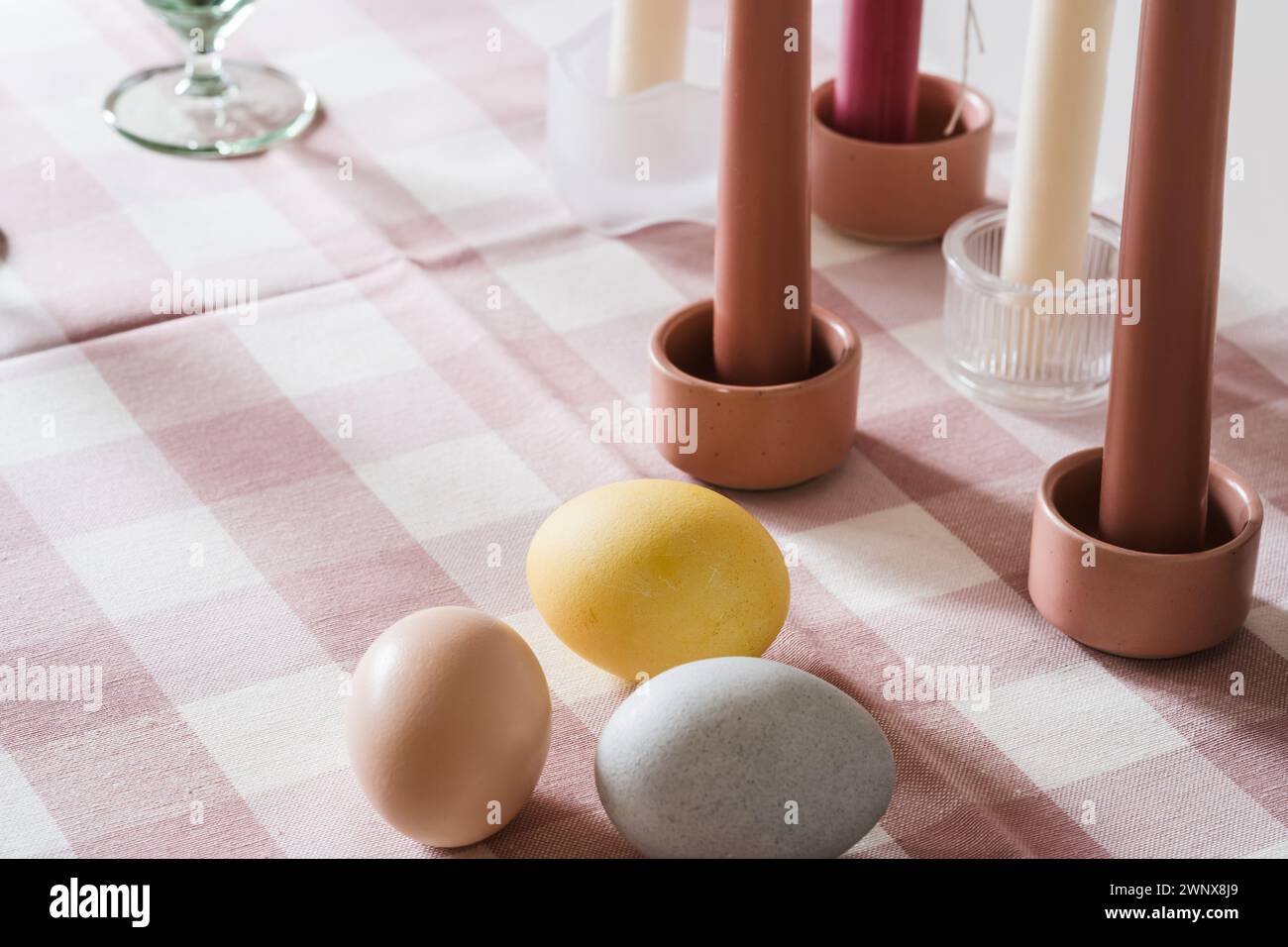 Easter place setting with candles and multi colored eggs, linen tablecloth Stock Photo
