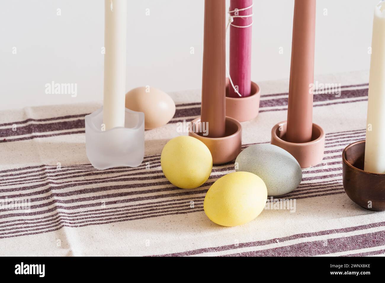 Easter place setting with candles and multi colored eggs, linen tablecloth Stock Photo