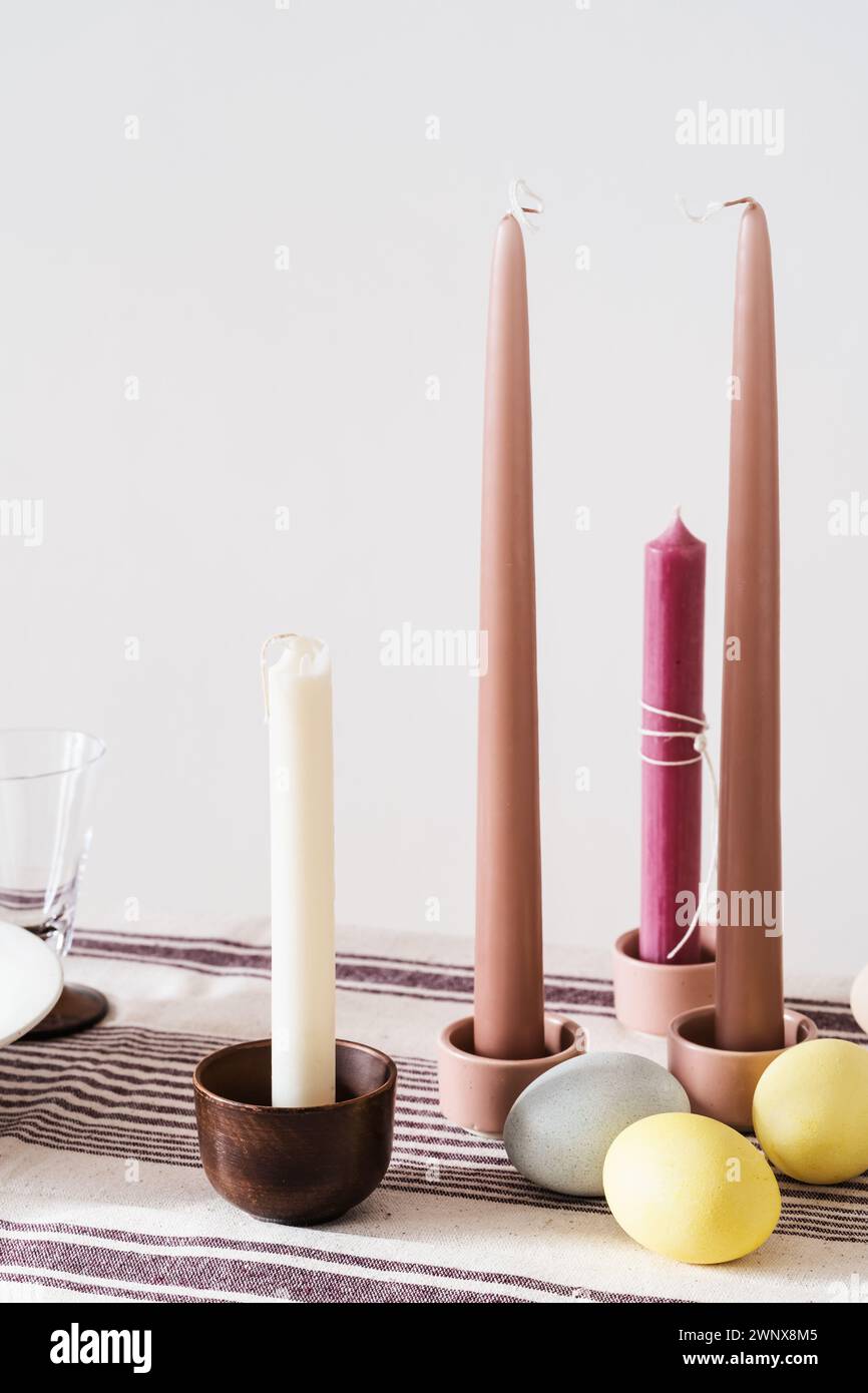 Easter place setting with candles and multi colored eggs, linen tablecloth Stock Photo