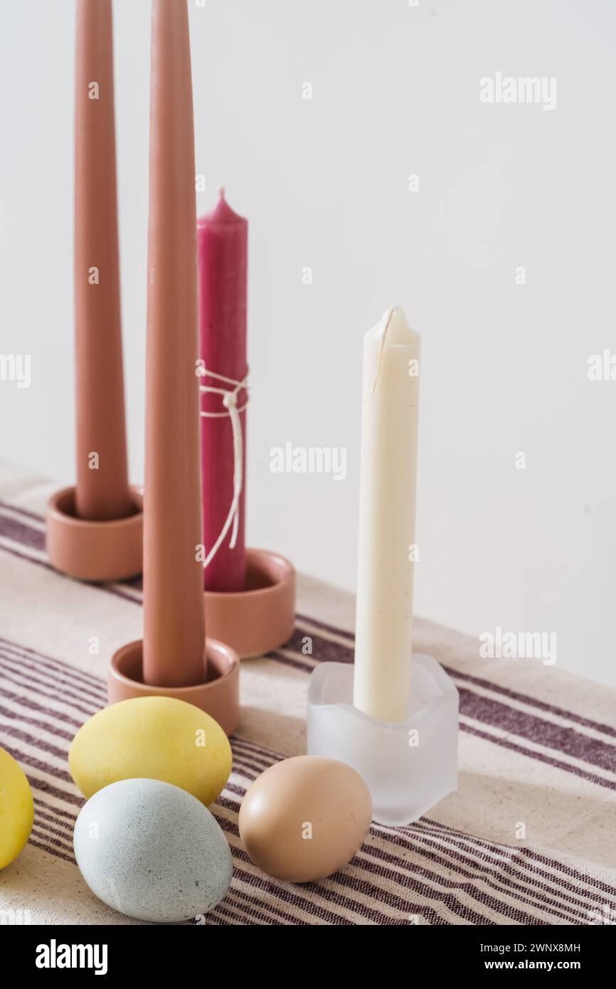 Easter place setting with candles and multi colored eggs, linen tablecloth Stock Photo
