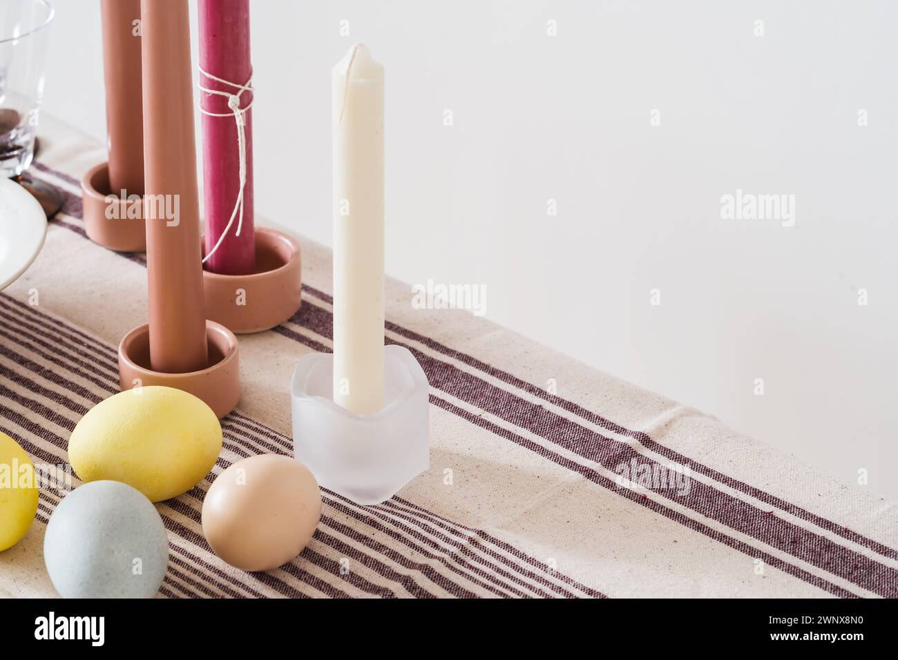 Easter place setting with candles and multi colored eggs, linen tablecloth Stock Photo