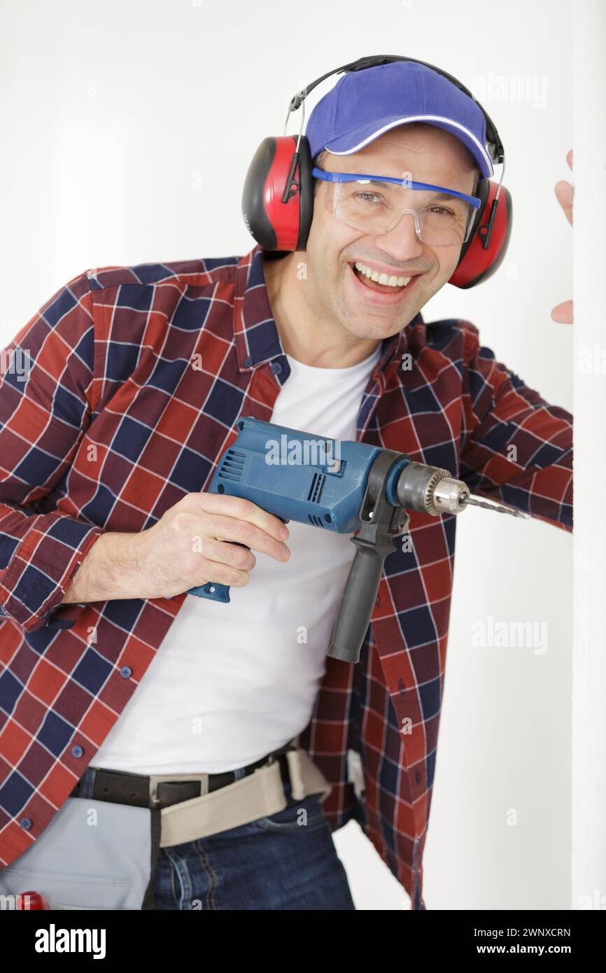 jovial mature man using a drill Stock Photo