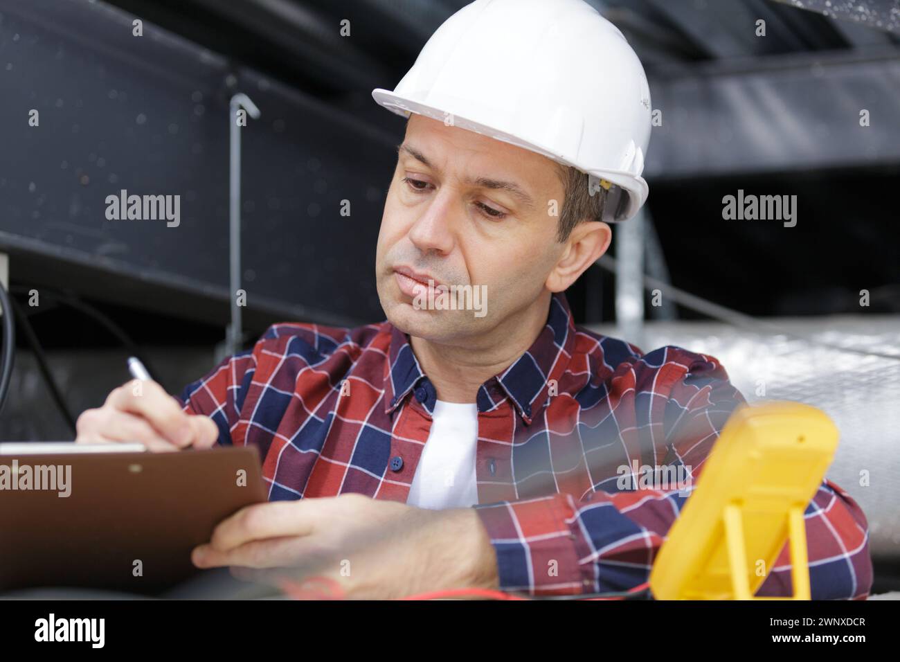 mature contractor writing on clipboard Stock Photo