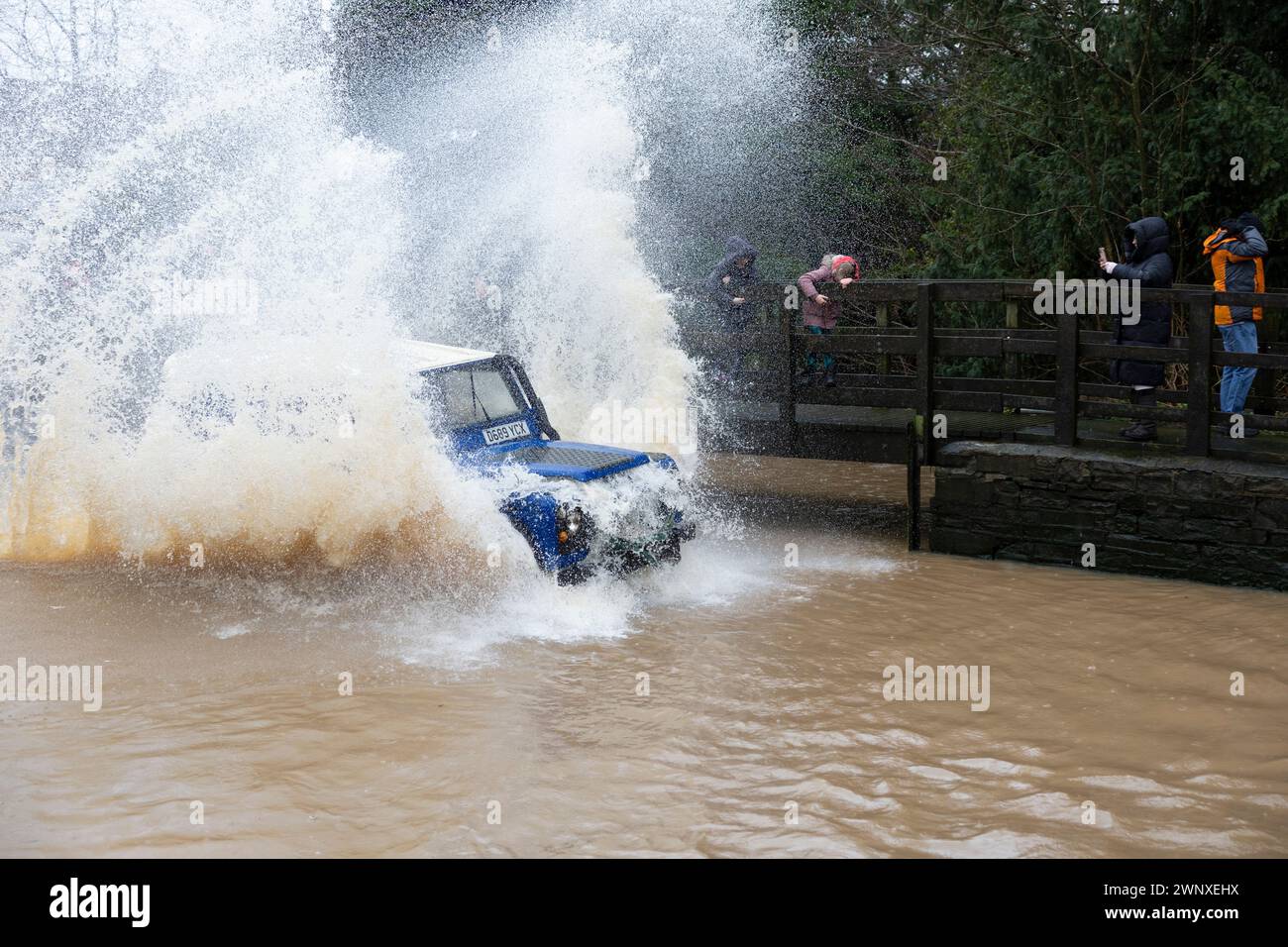 20/02/22   Land Rover Defender splashes young spectators.  As heavy rain and river levels rise, more than sixty spectators turn-out to watch 4X4 drive Stock Photo
