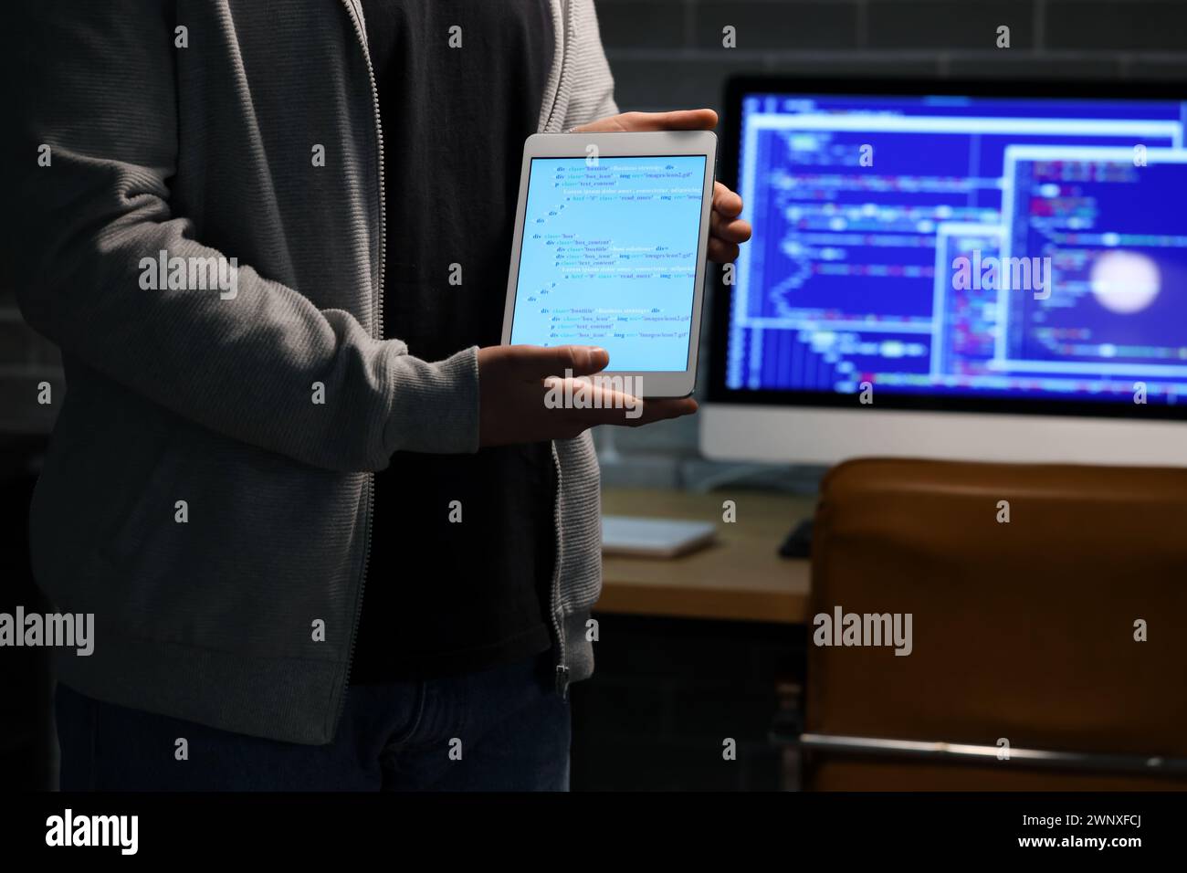 Hacker with tablet computer in dark room, closeup Stock Photo