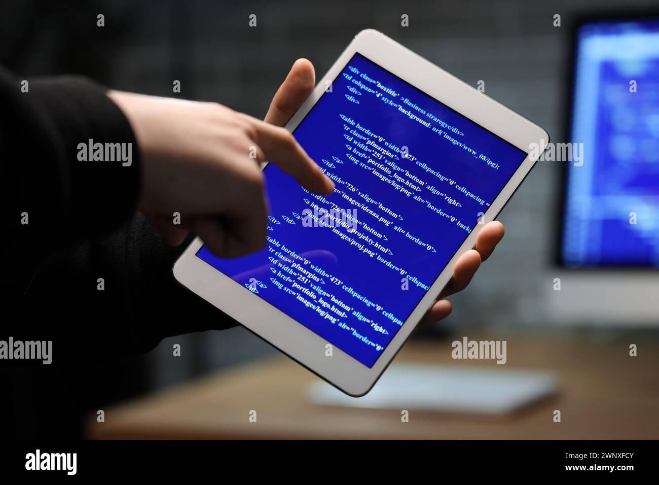 Hacker using tablet computer in dark room, closeup Stock Photo