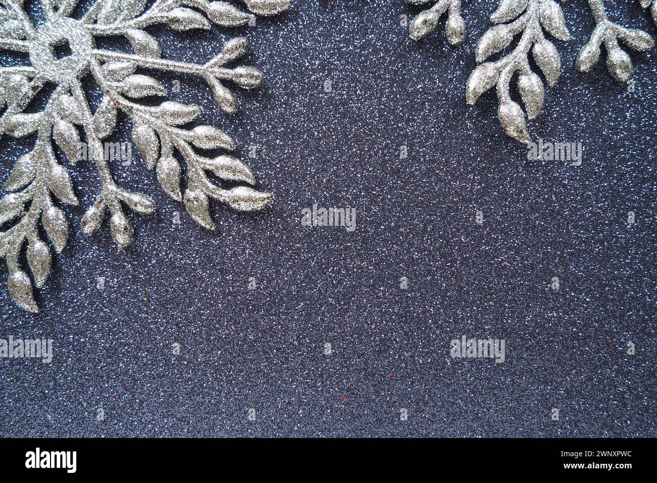 Two large silver flat ornate snowflakes are laid out on velvety dark blue paper. Free space for text. New Year or Christmas background for advertising Stock Photo