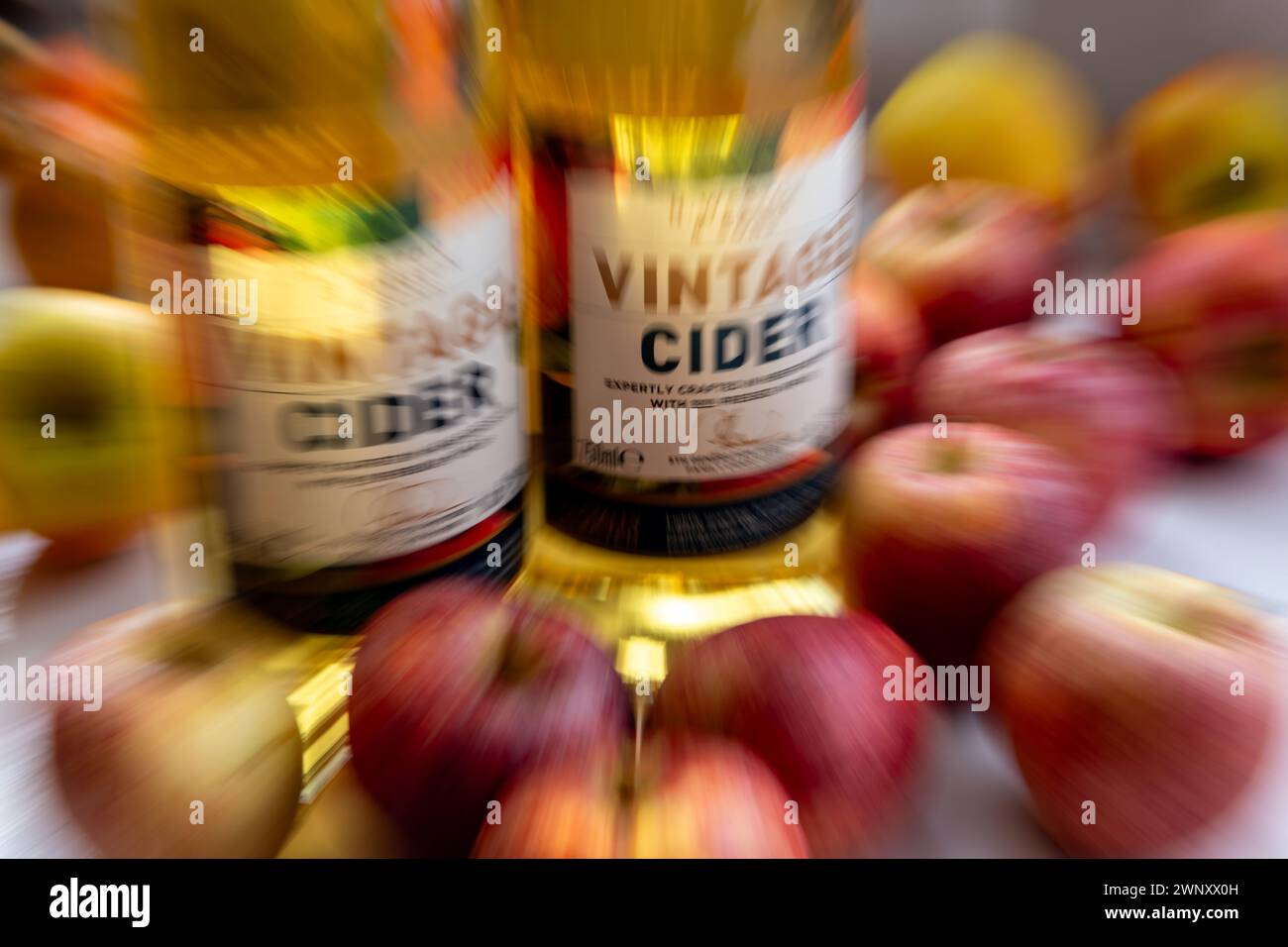 A zoom burst background of bottles of vintage cider surrounded by apples. Stock Photo