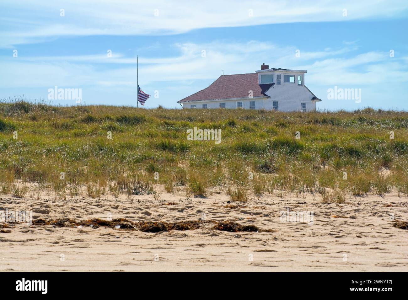 Oversand Permit Station at Race Point beach, on sand dune.  Built in 1888 for Life-Saving Service as a stable for coastal shipwreck rescues. USA flag Stock Photo