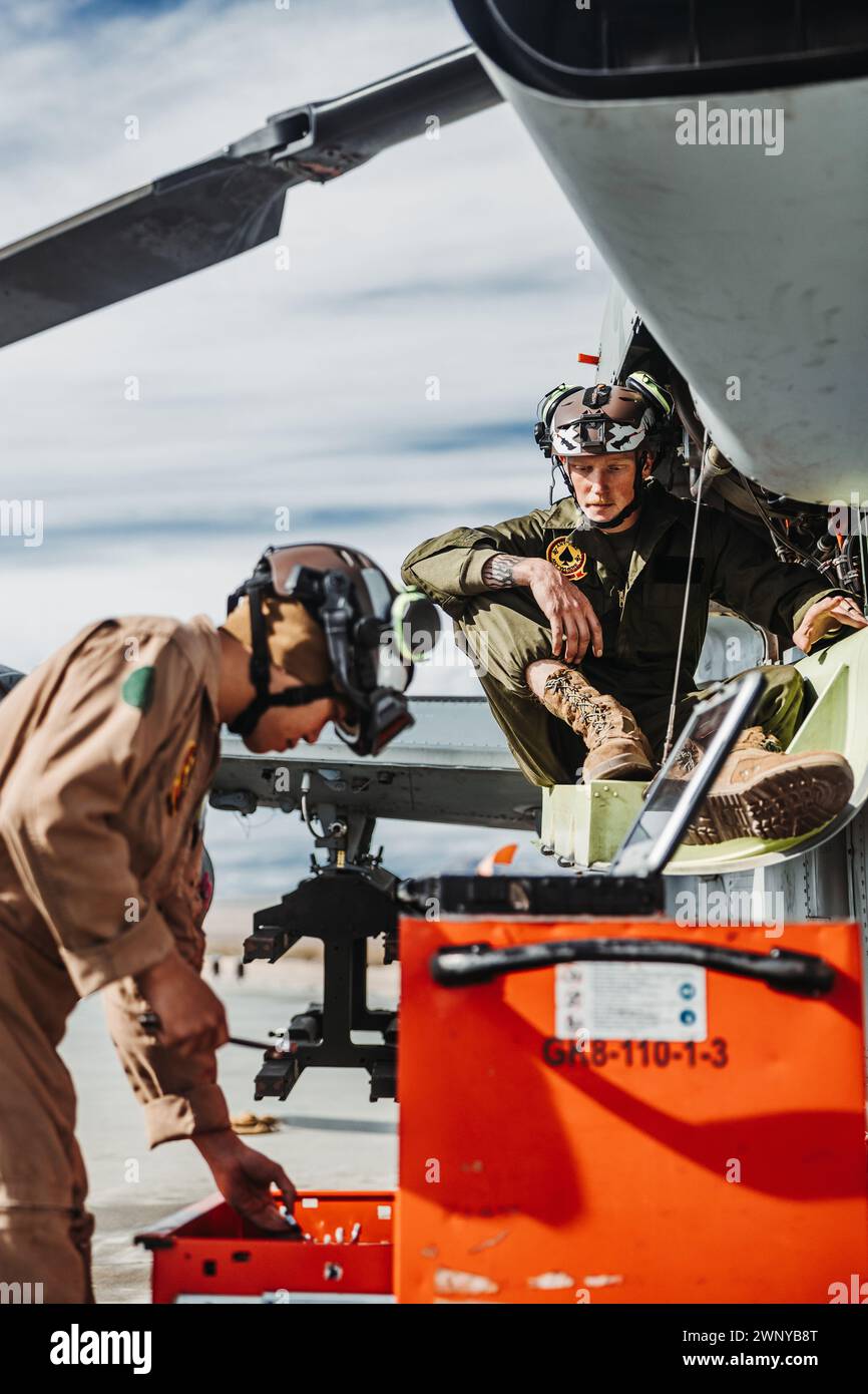 U.S. Marine Corps Cpl. Austin Potter, a Roosevelt, Utah native, right, and Sgt. Ivandominick Uy, a Manila, Philippines native, both AH-1Z Viper mechanics with Marine Light Attack Helicopter Squadron (HMLA) 267, Marine Aircraft Group 39, 3D Marine Aircraft Wing, conduct maintenance on a Viper in support of a Marine Air-Ground Task Force Warfighting Exercise during Service Level Training Exercise 2-24 at Camp Wilson, Marine Corps Air-Ground Combat Center, Twentynine Palms, California, Feb. 19, 2024. MWX is the culminating event for SLTE 2-24 that improves U.S. and allied service members’ operati Stock Photo