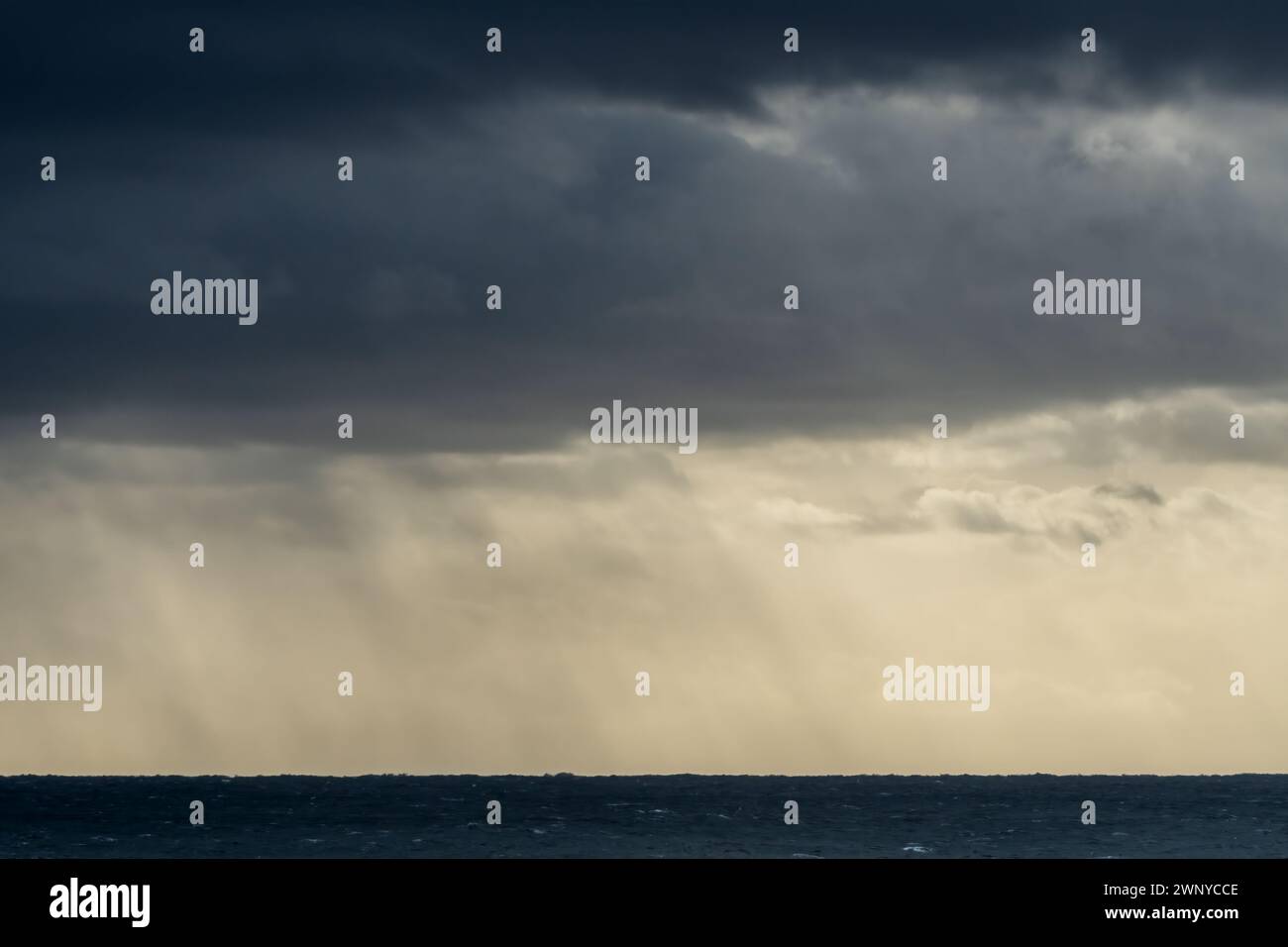 Stormy sky with dark clouds and rain falling on the horizon of the ocean. Graphic resources background. Stock Photo