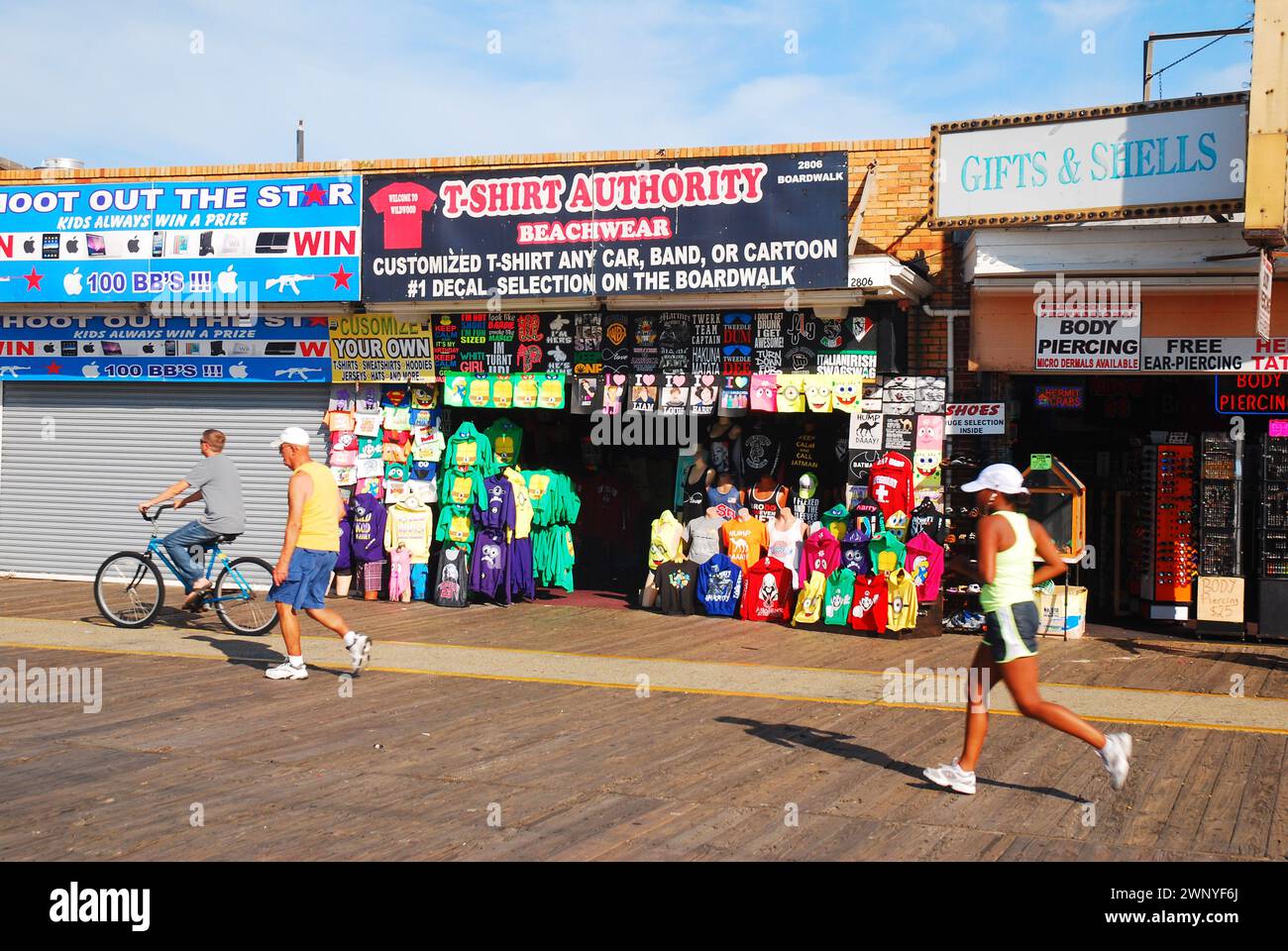 A young woman jogs along the Wildwood New Jersey boardwalk passing the souvenir stores Stock Photo