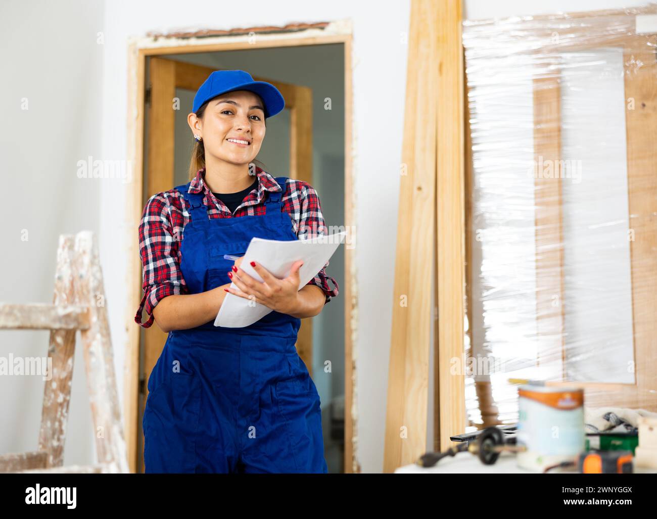 Positive woman builder with documents in apartment Stock Photo