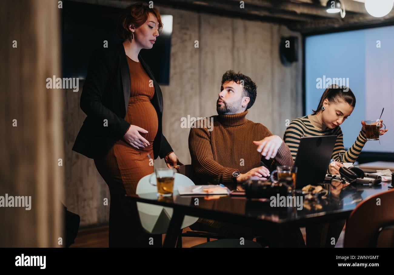 Young professionals working late, collaborating on a project for business growth, discussing sales statistics, revenue, and budgeting for expansion. Stock Photo