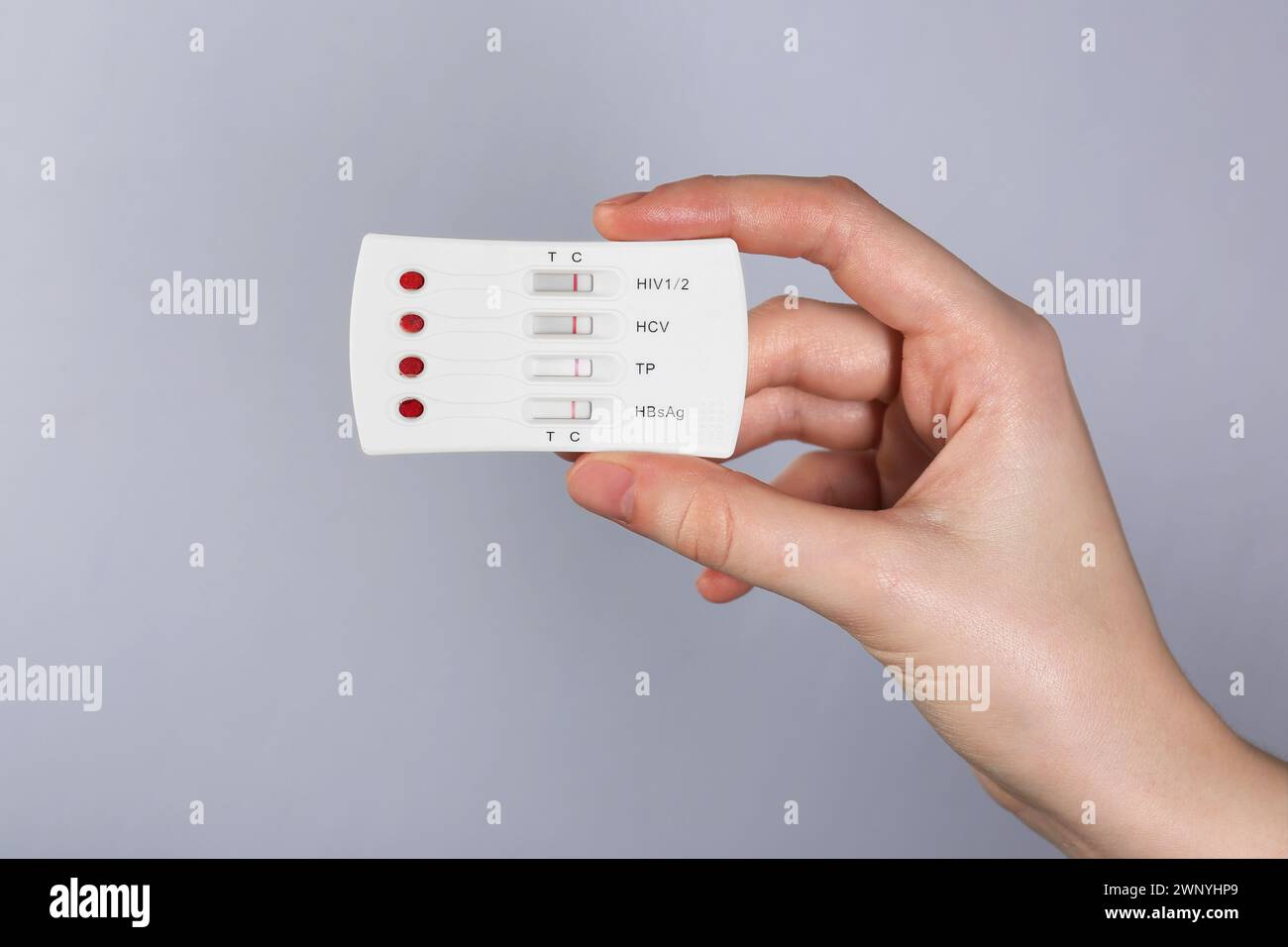 Woman holding disposable multi-infection express test on light grey ...