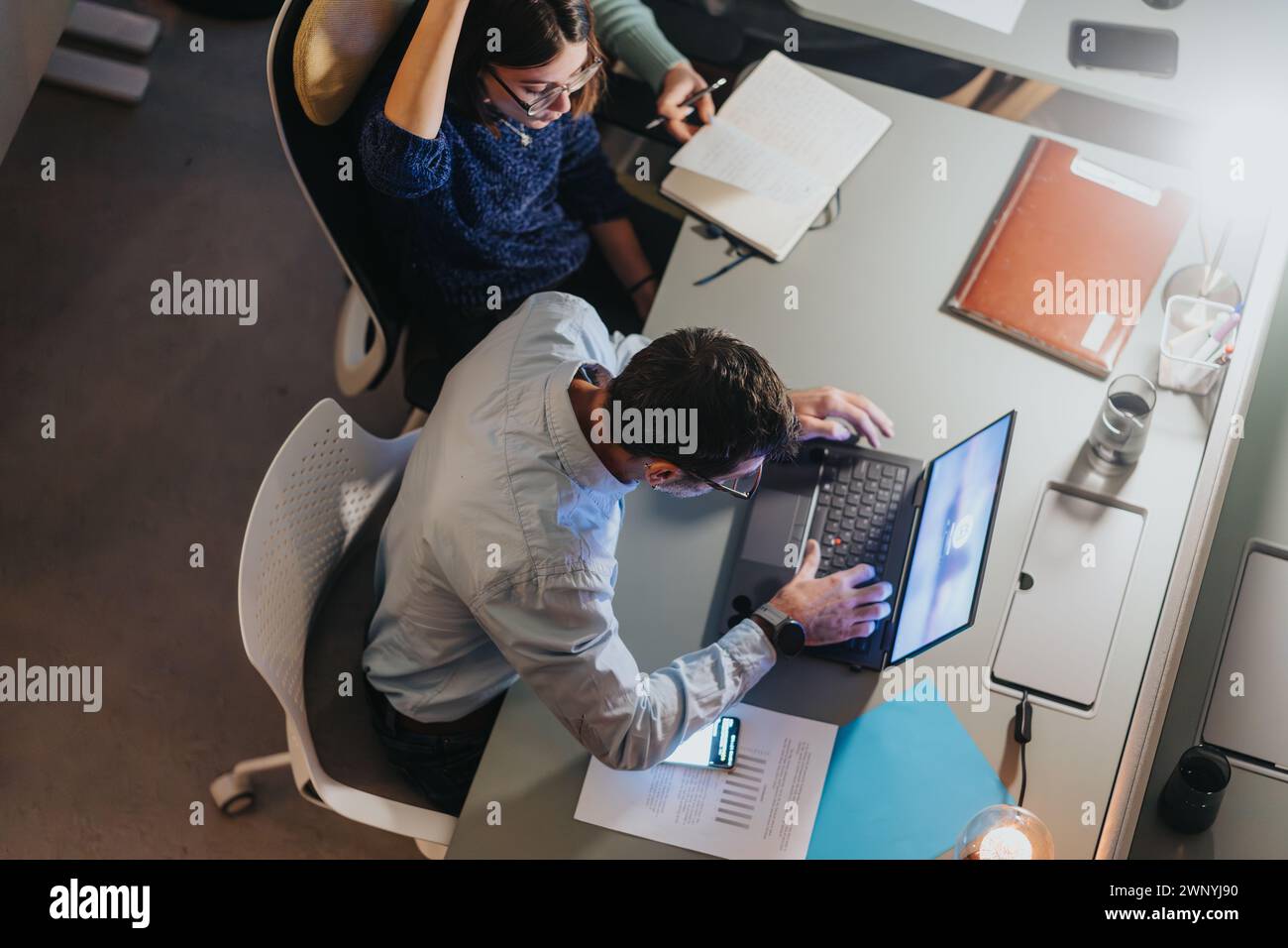 Focused employee engaged in busy work environment at modern office desk ...