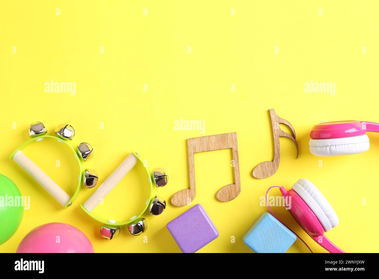 Baby song concept. Wooden notes, tambourines and toys on yellow