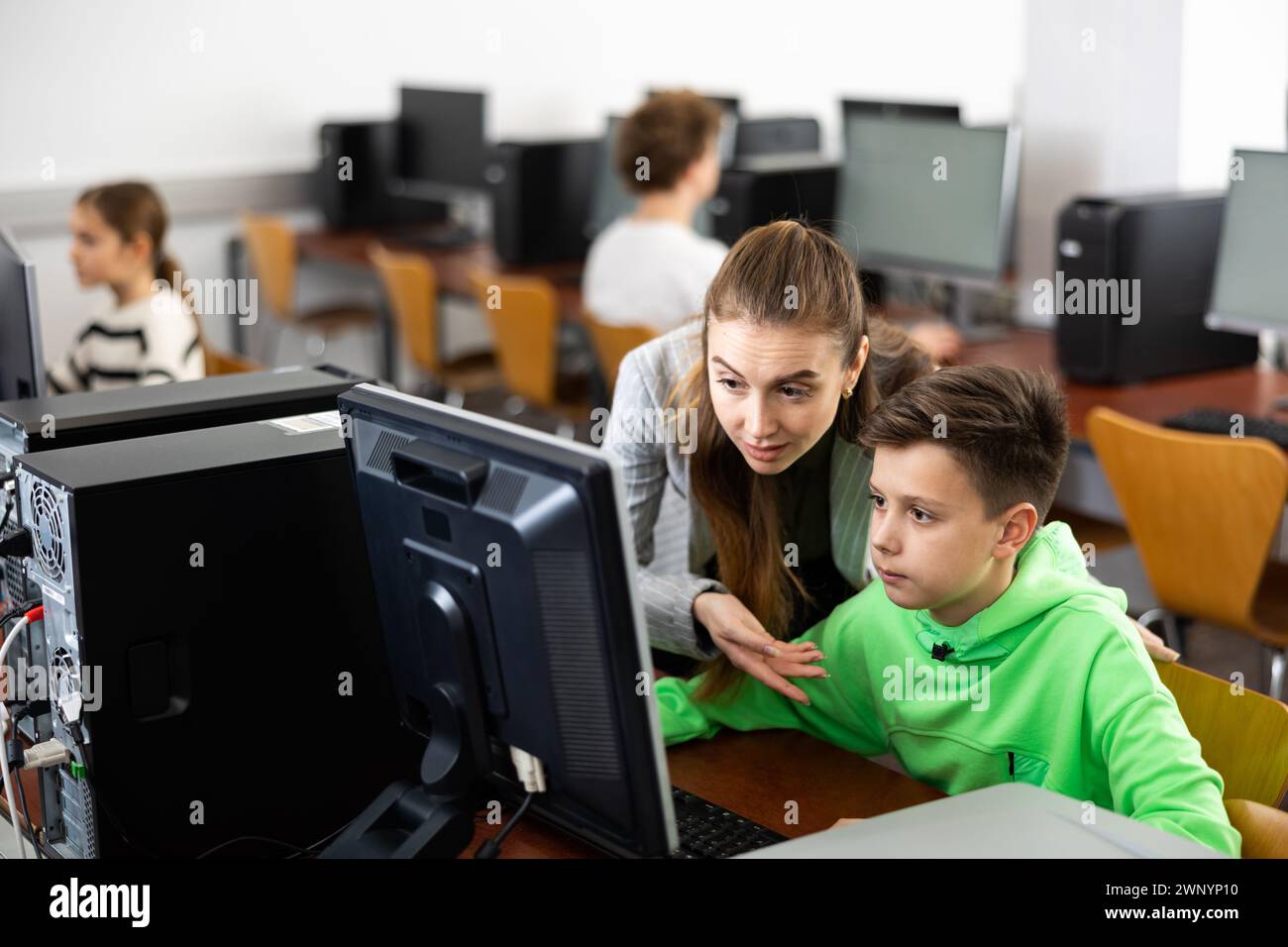 Woman teacher helps guy with learning on computer in class Stock Photo ...