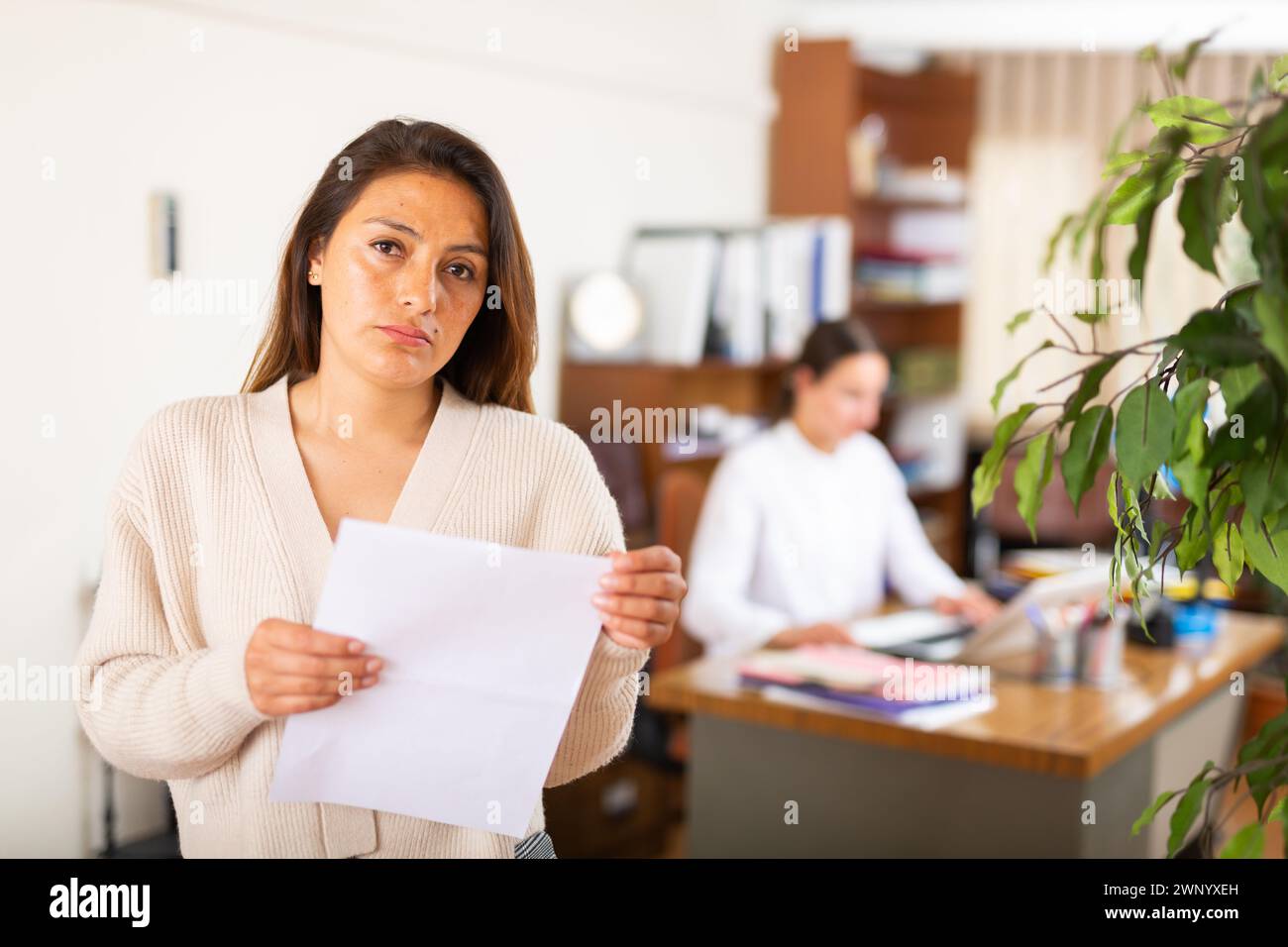 Unhappy woman standing in office after reprimand from chief Stock Photo